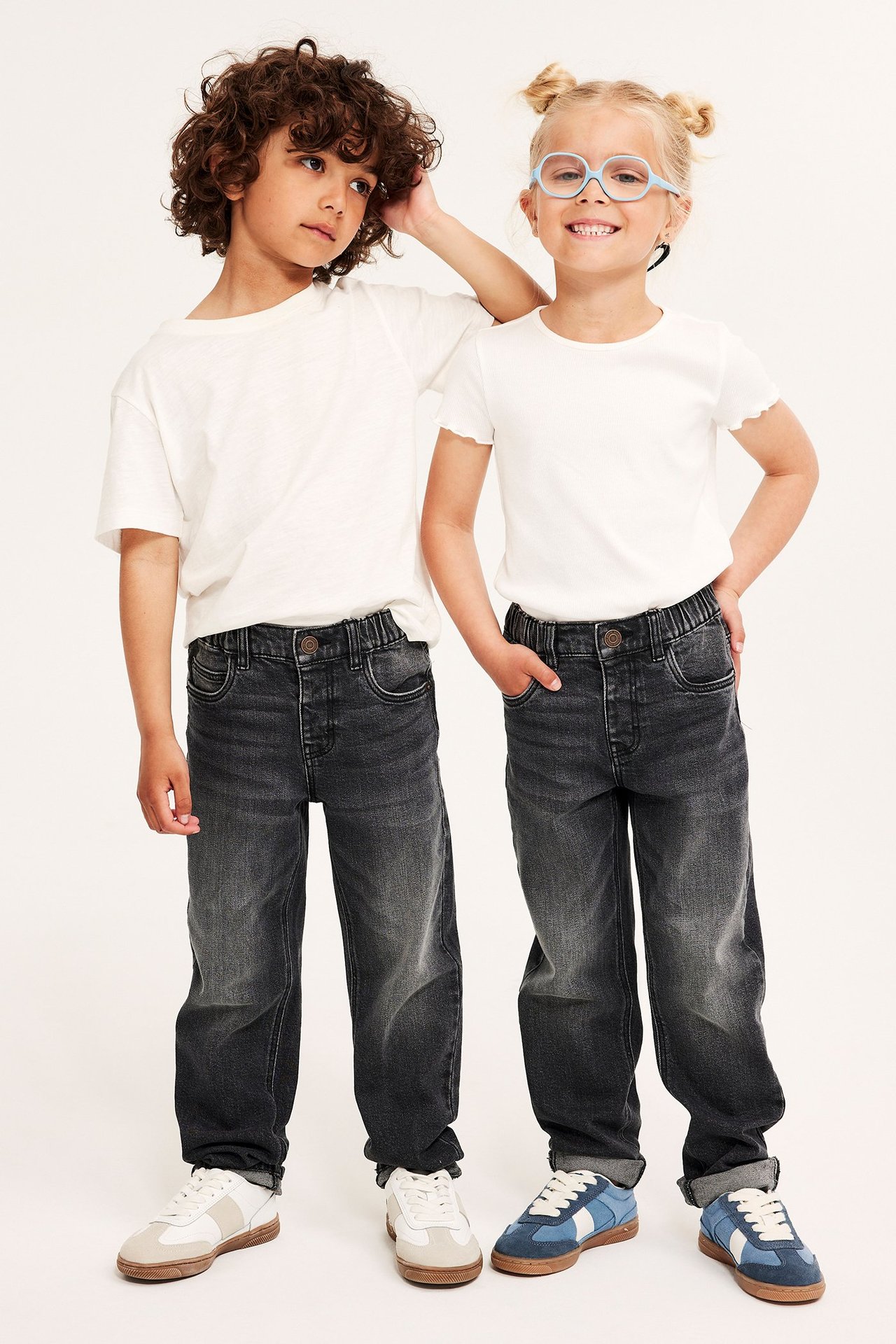 Forfra: to barn i grå, avslappede jeans med elastisk midje og hvite t-skjorter.