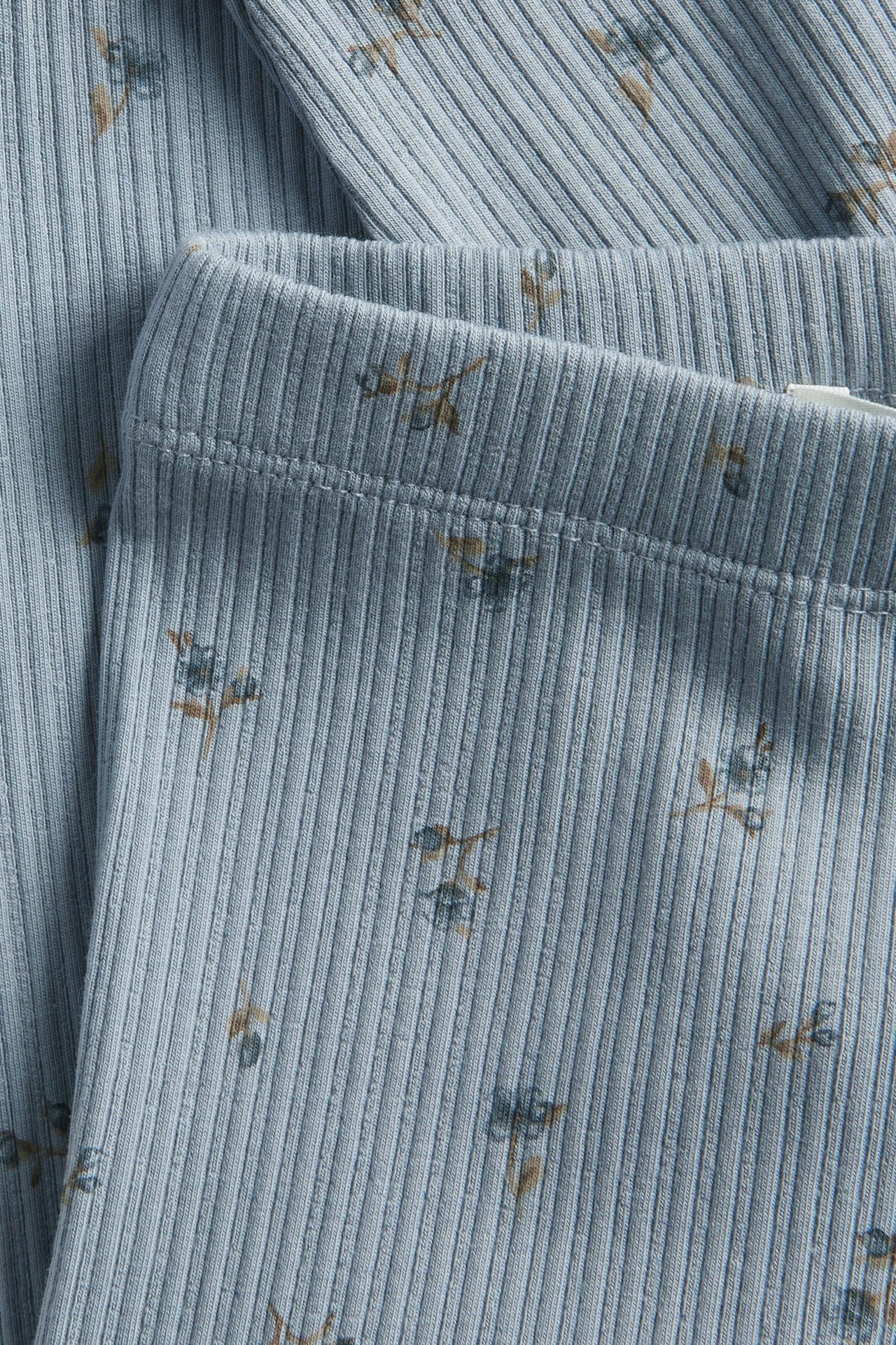 Lähikuva vaaleansinisistä ribatuista leggingseistä, joissa on hienovarainen kukkakuvio.