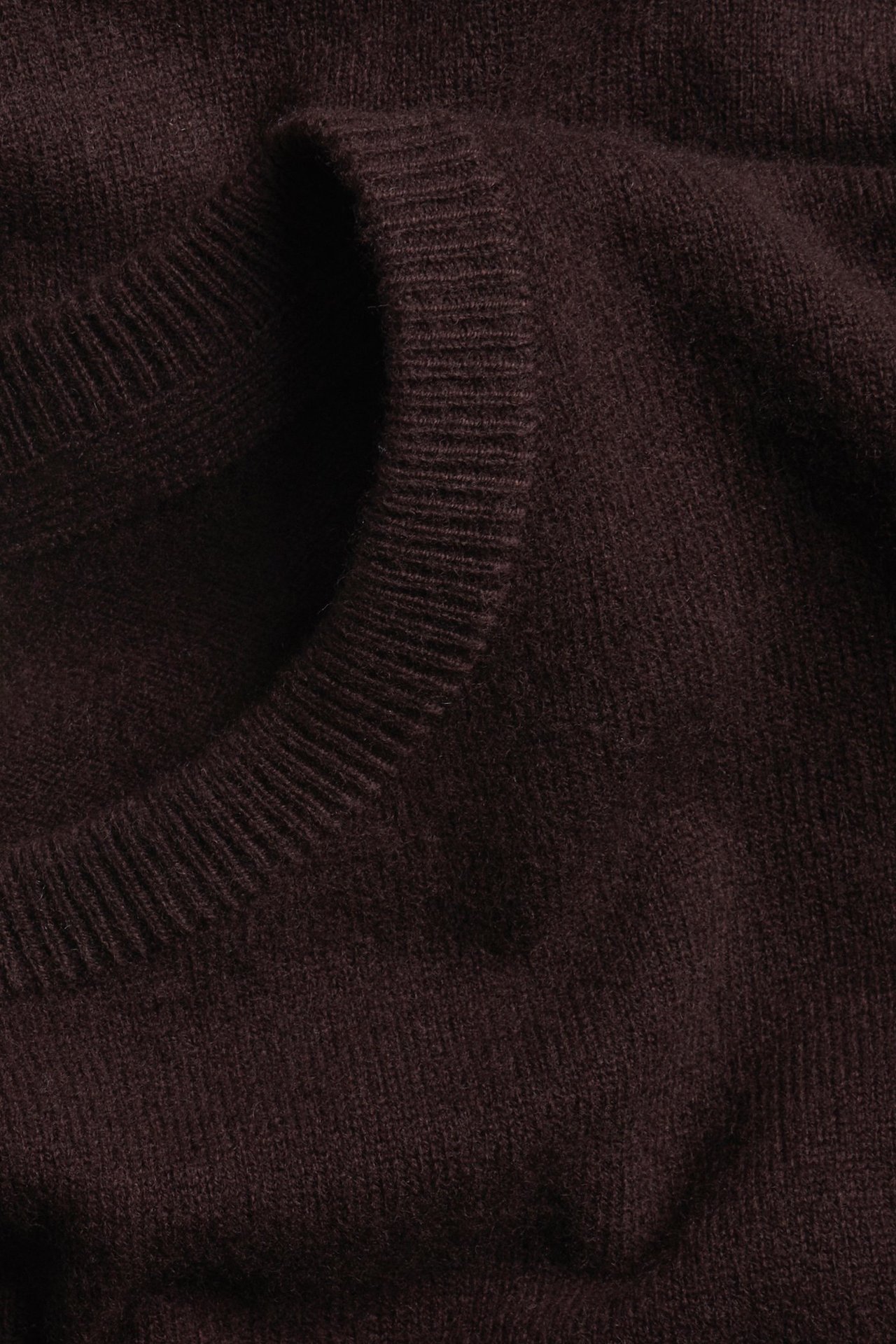 Zbliżenie na męski bordowy sweter z okrągłym dekoltem, wykonany ze 100% wełny.