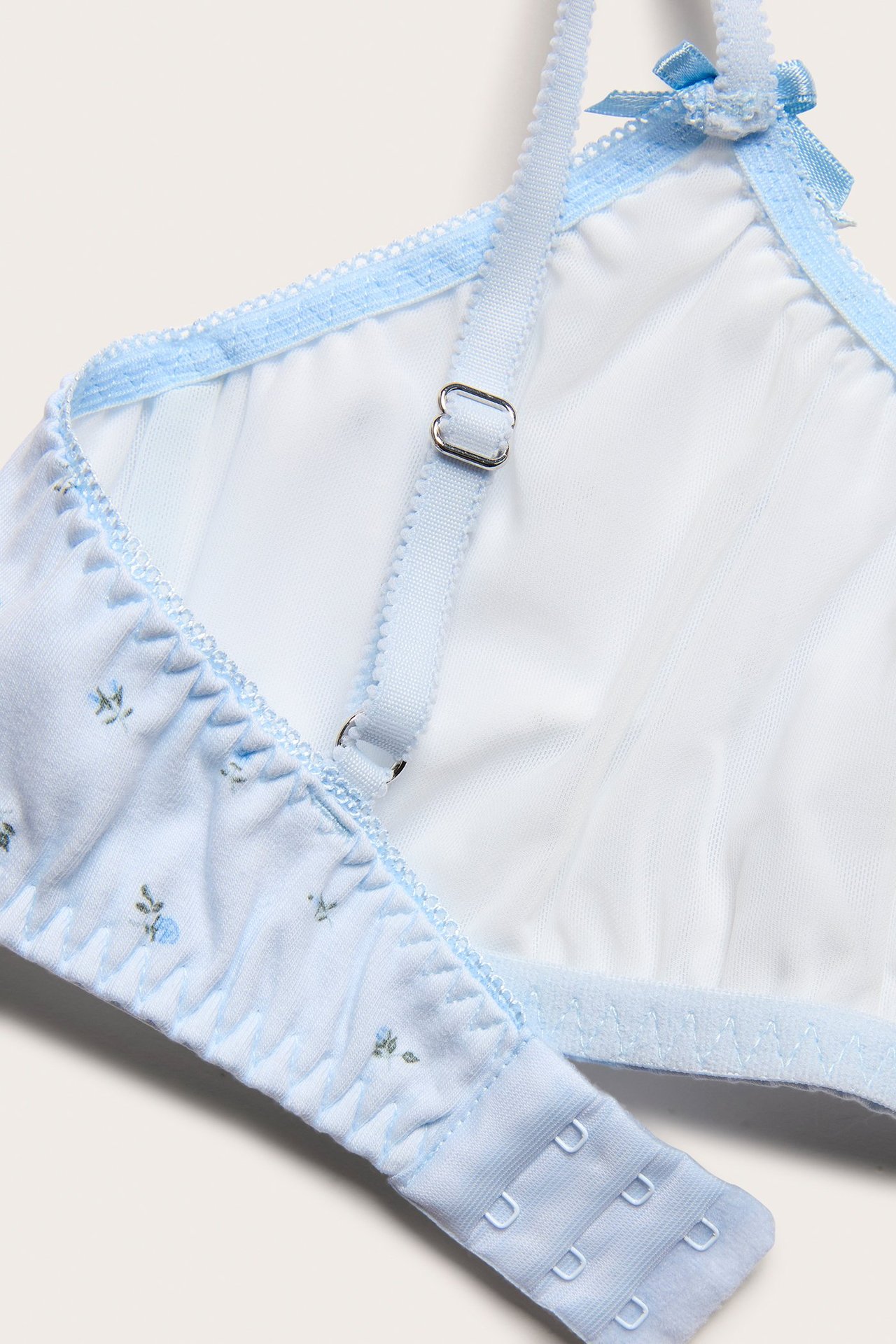 Zbliżenie jasnoniebieskiego biustonosza bez fiszbin z kwiatowym wzorem, regulowanymi ramiączkami i zapięciem z tyłu.