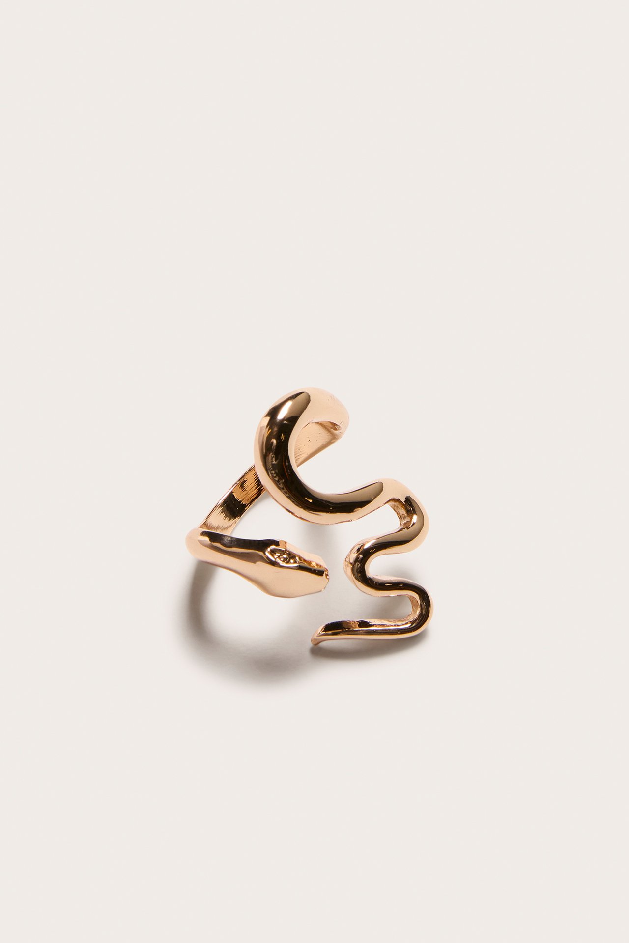 Närbild uppifrån av en guldfärgad ormformad ring i metall.
