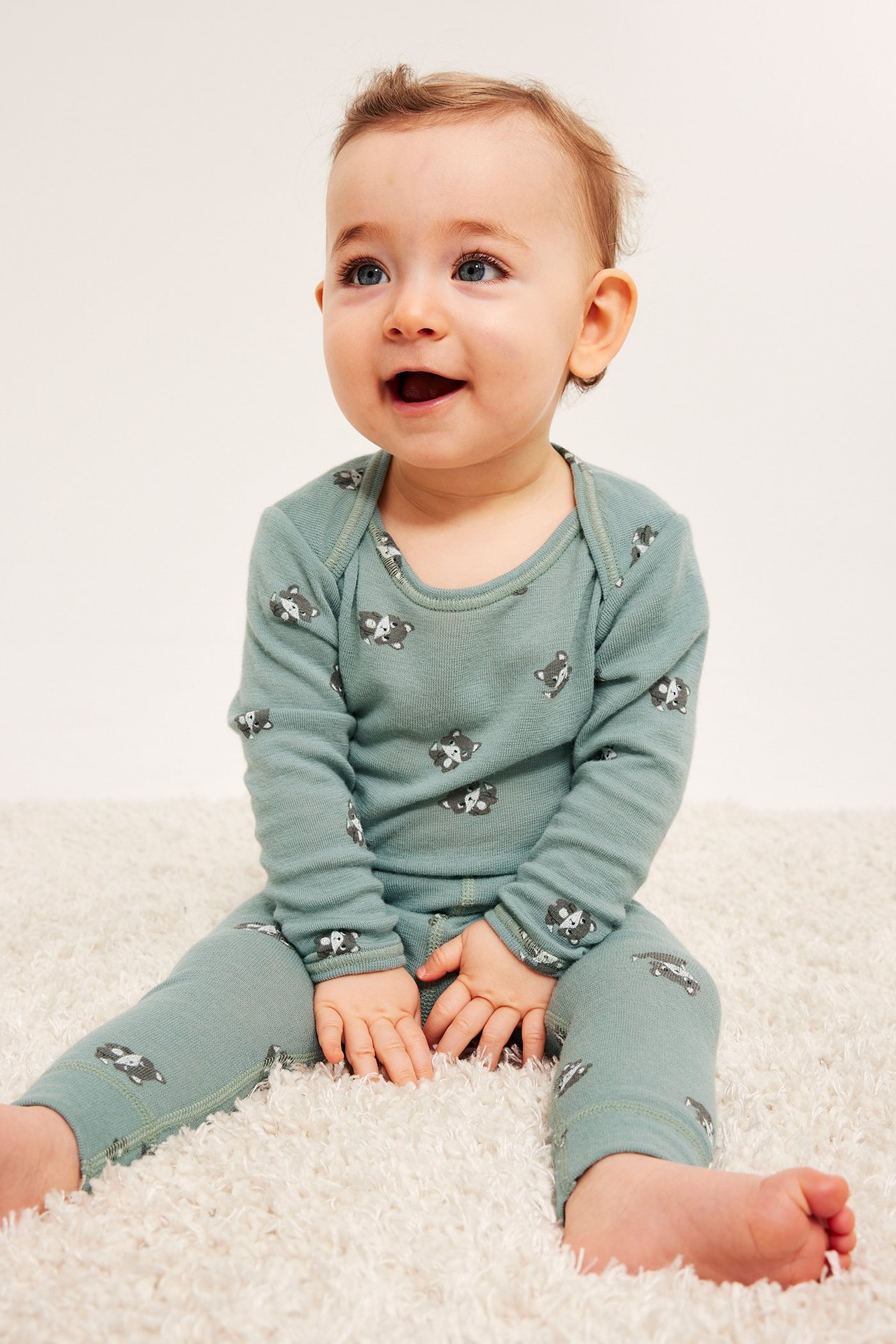 Edestä: vauva yllään vaaleanvihreä merinovillainen body ja housut kettukuviolla.