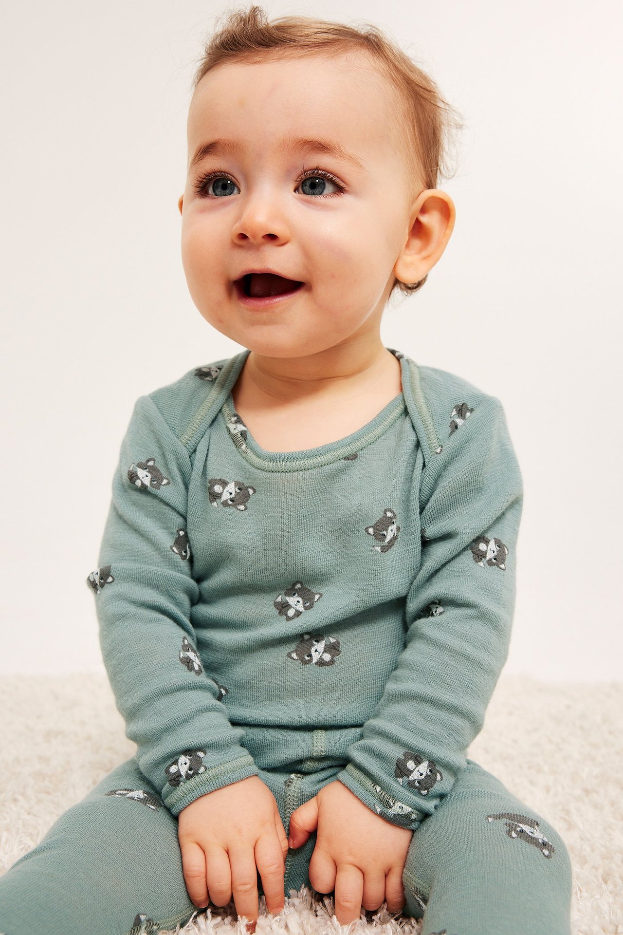 Edestä kuvattu vauva yllään vaaleanvihreä merinovillainen body kettukuviolla ja yhteensopivat housut.