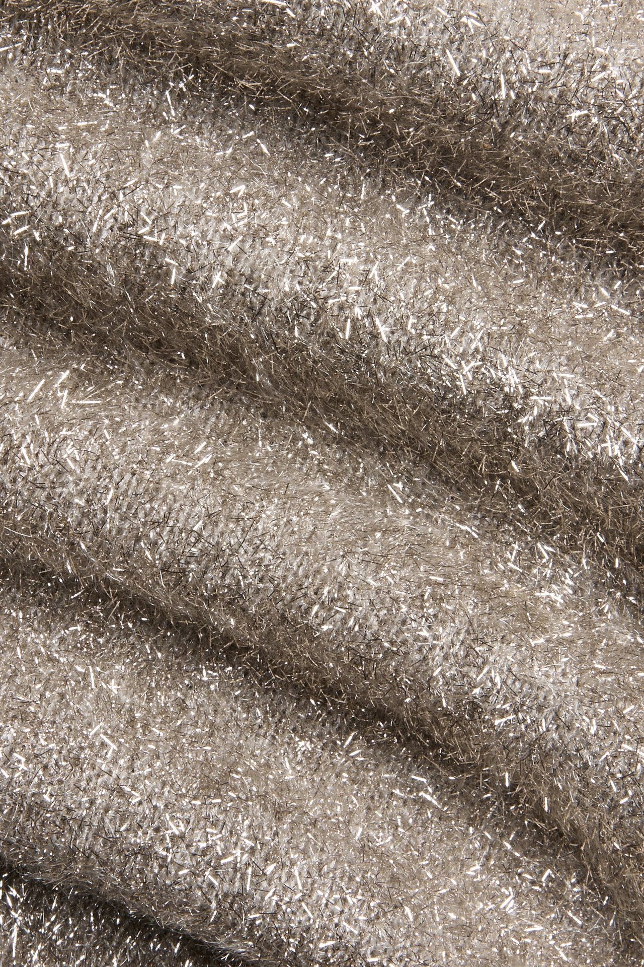 Zbliżenie jasnobeżowej dzianiny brokatowej z subtelnymi falami i błyszczącymi nitkami.