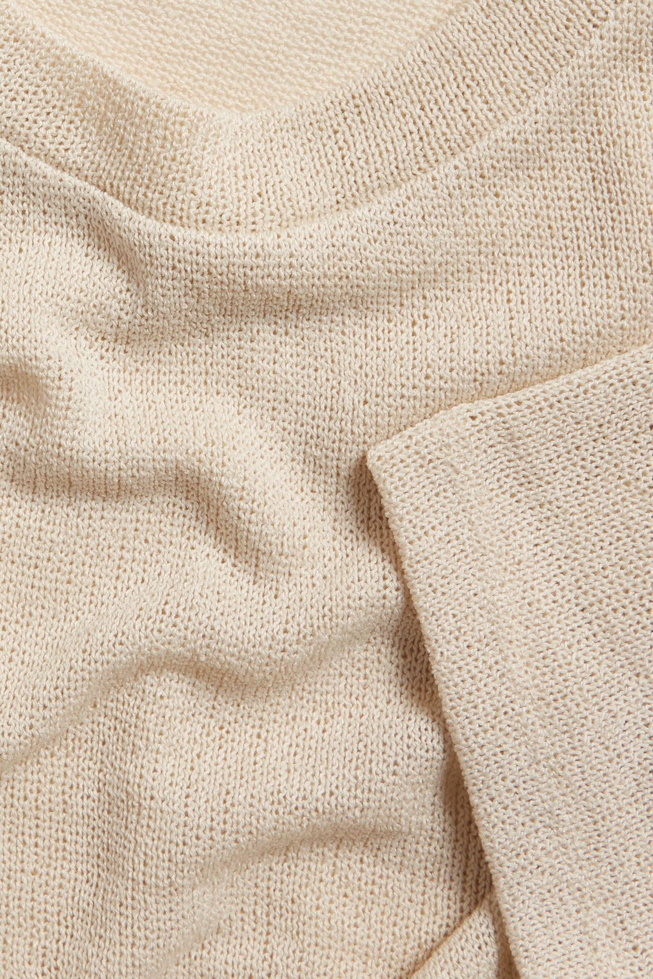 Zbliżenie na kremowy, strukturalny T-shirt z poliestru imitującego len, widoczny dekolt i rękaw.