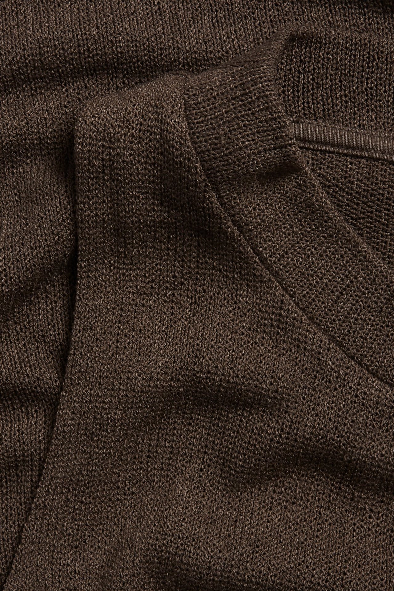 Zbliżenie na ciemnobrązowy, teksturowany top z poliestru z dekoltem w serek.