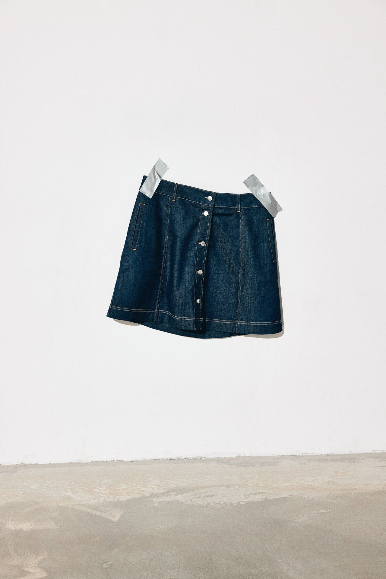 Framifrån: mörkblå A-linje jeanskjol med knappar fram och fickor.