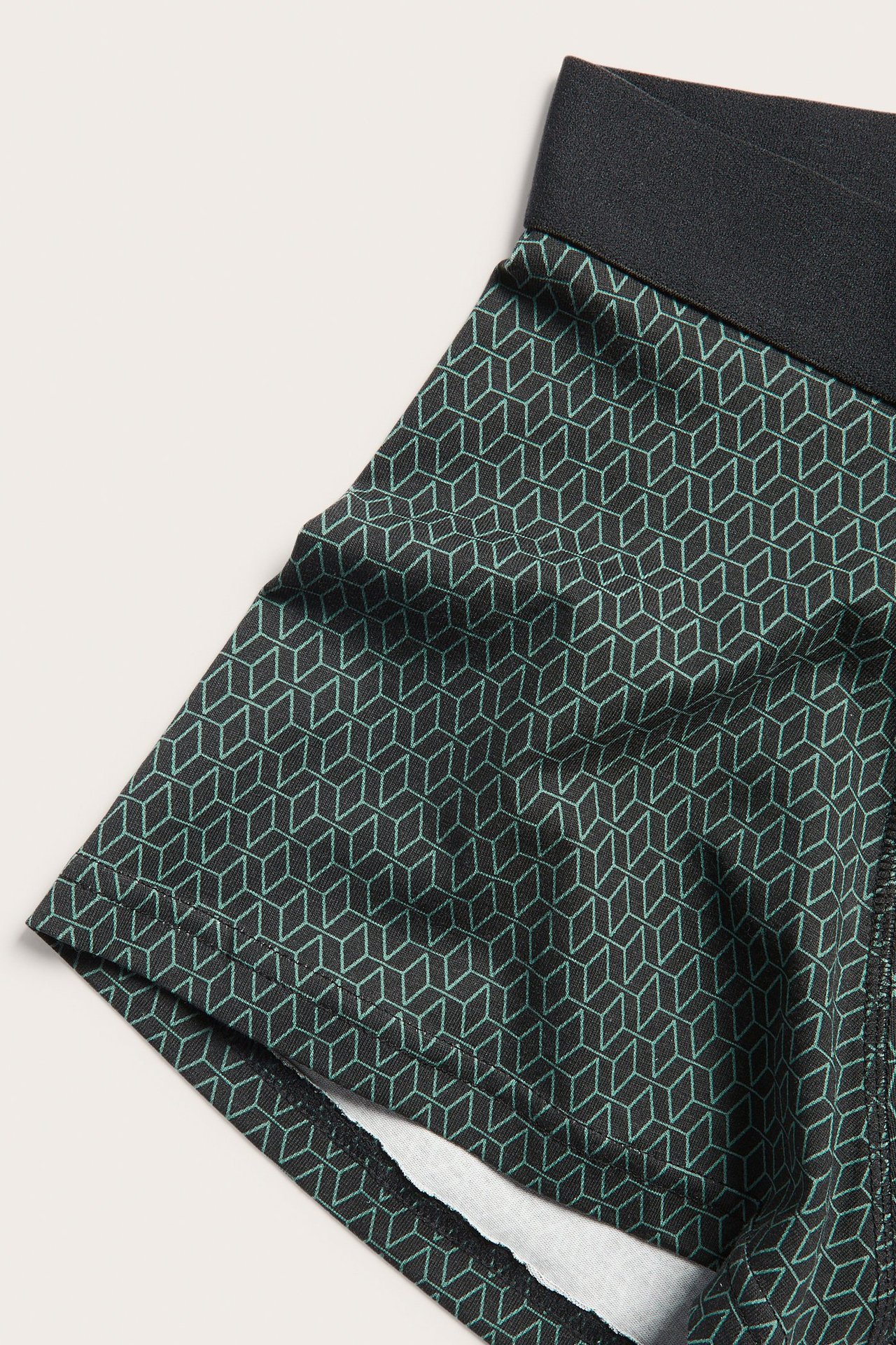 Nærbilde av svarte bokser for menn med grønt geometrisk mønster og svart elastisk linning.