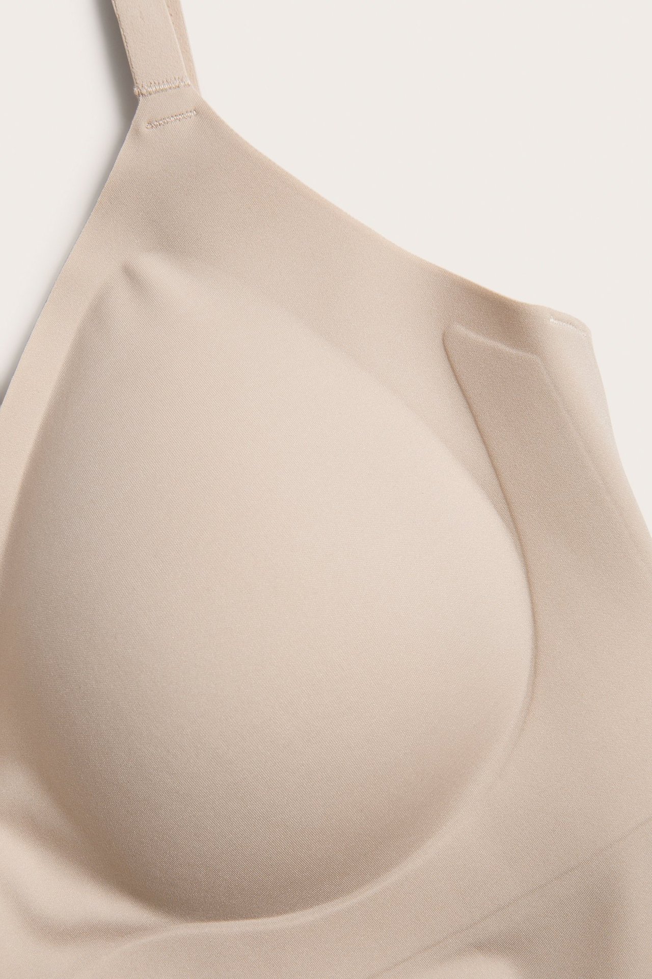 Zbliżenie jasnoróżowego miękkiego body z usztywnianą miseczką i regulowanym ramiączkiem.