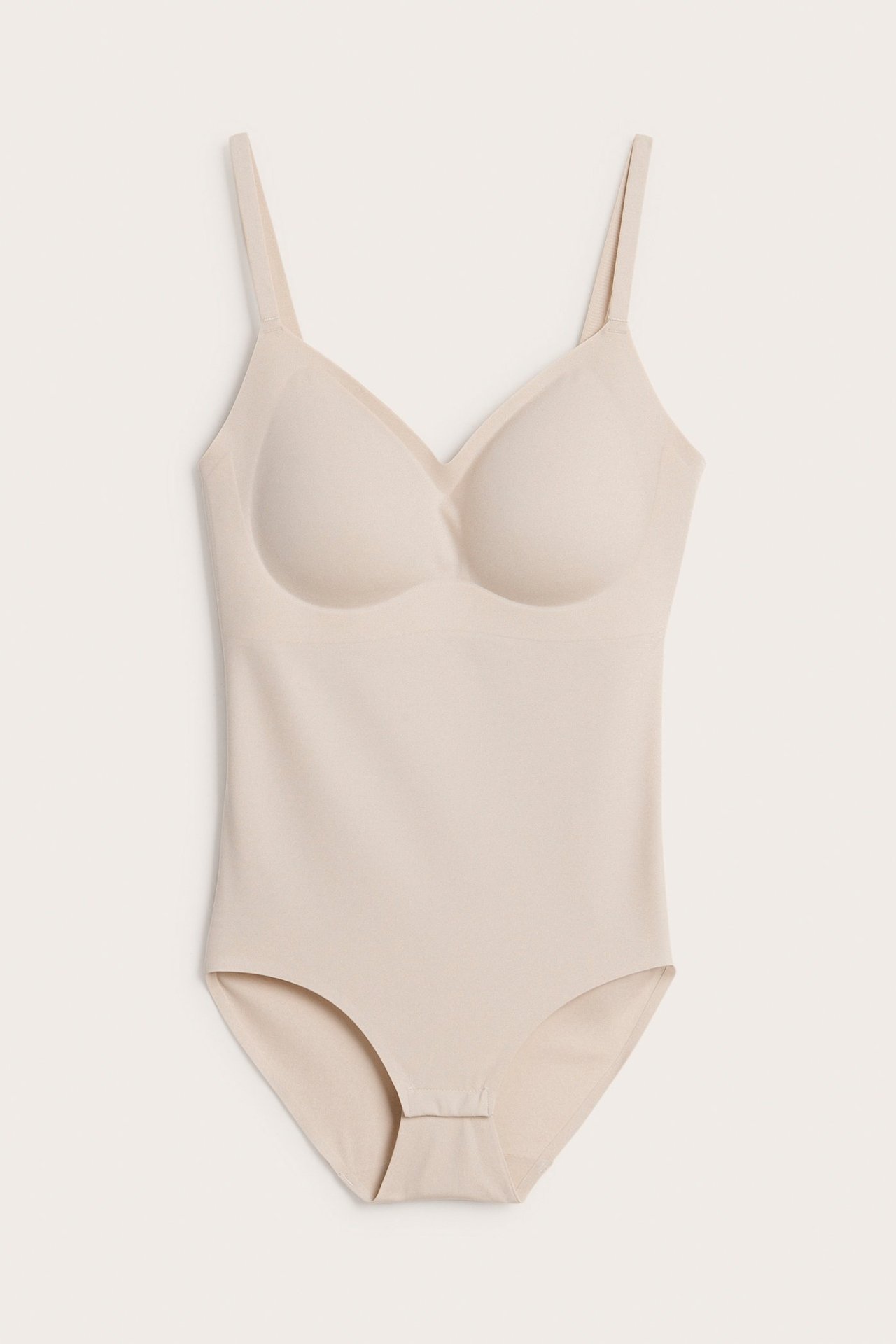 Edestä näkymä vaaleanpunaisesta saumattomasta pehmeästä bodysta, jossa säädettävät olkaimet ja topatut kupit.