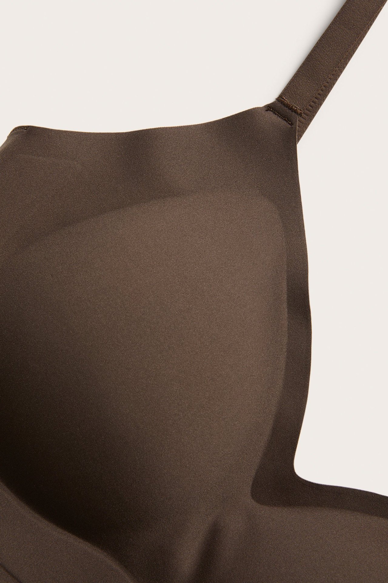 Zbliżenie na ciemnobrązowe miękkie body z usztywnianą miseczką i regulowanym ramiączkiem.