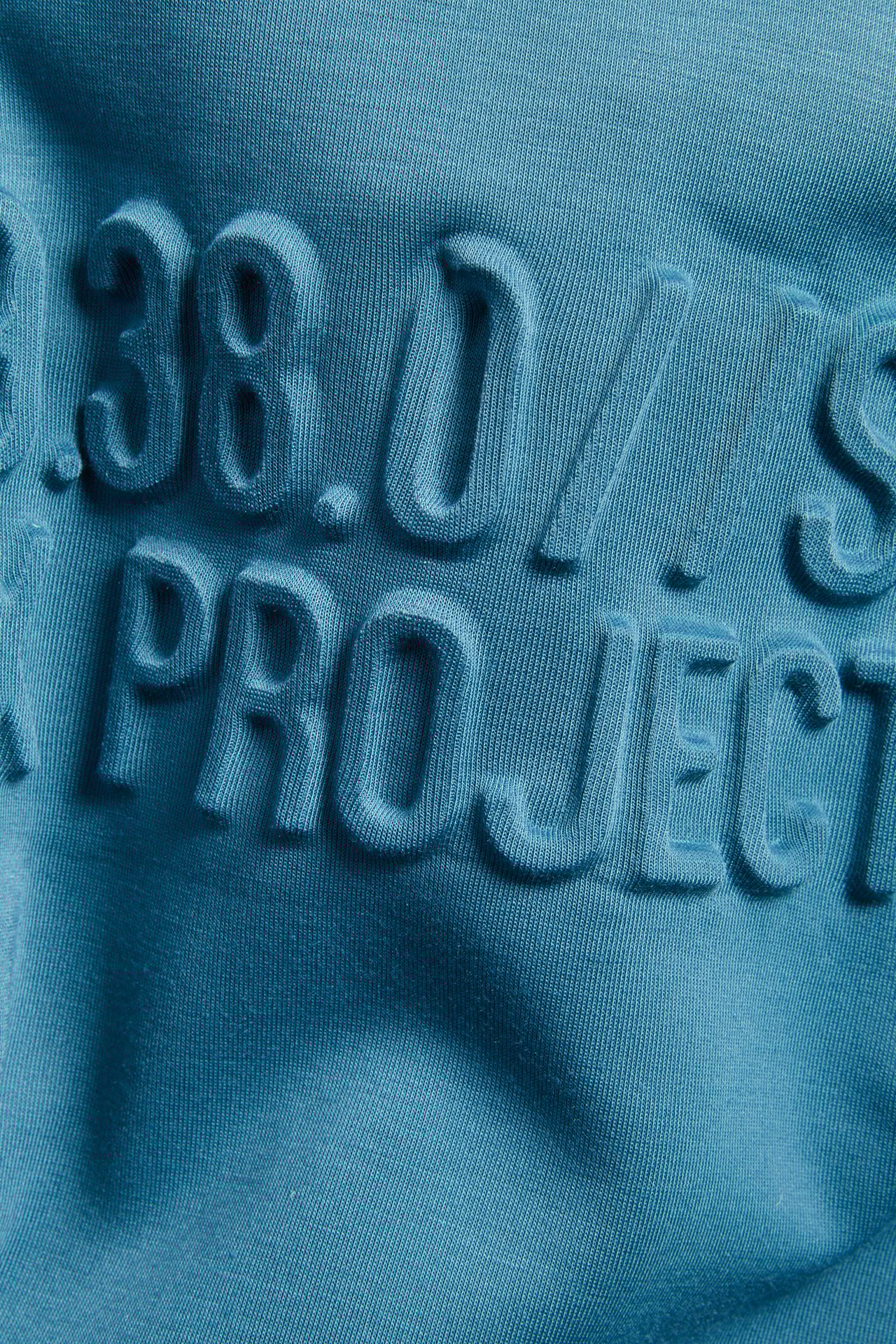 Zbliżenie na turkusową zieloną bluzę z kapturem z wypukłym nadrukiem 3D z tekstem.