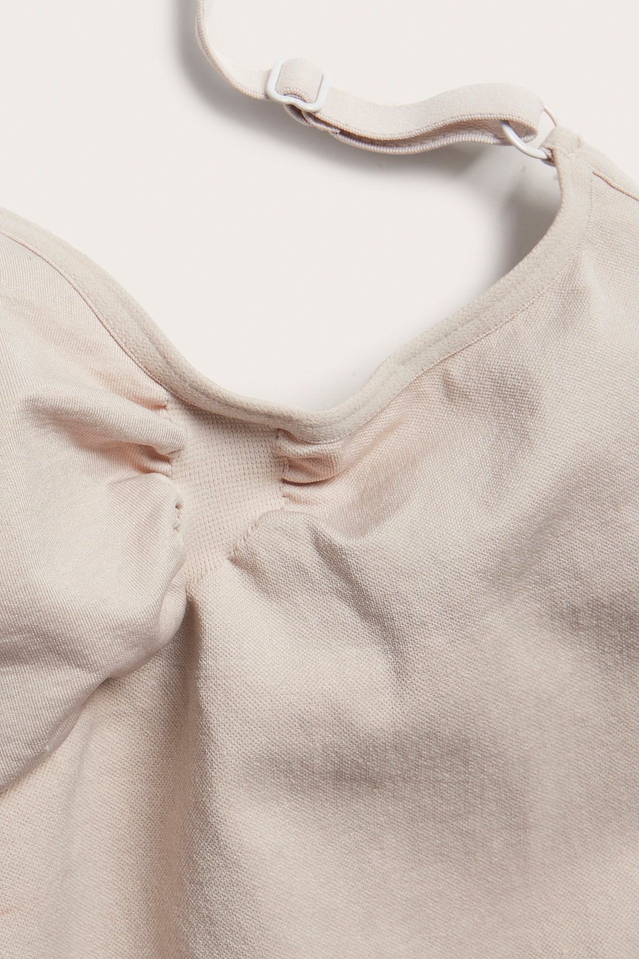 Zbliżenie beżowego, bezszwowego body modelującego z regulowanymi ramiączkami.