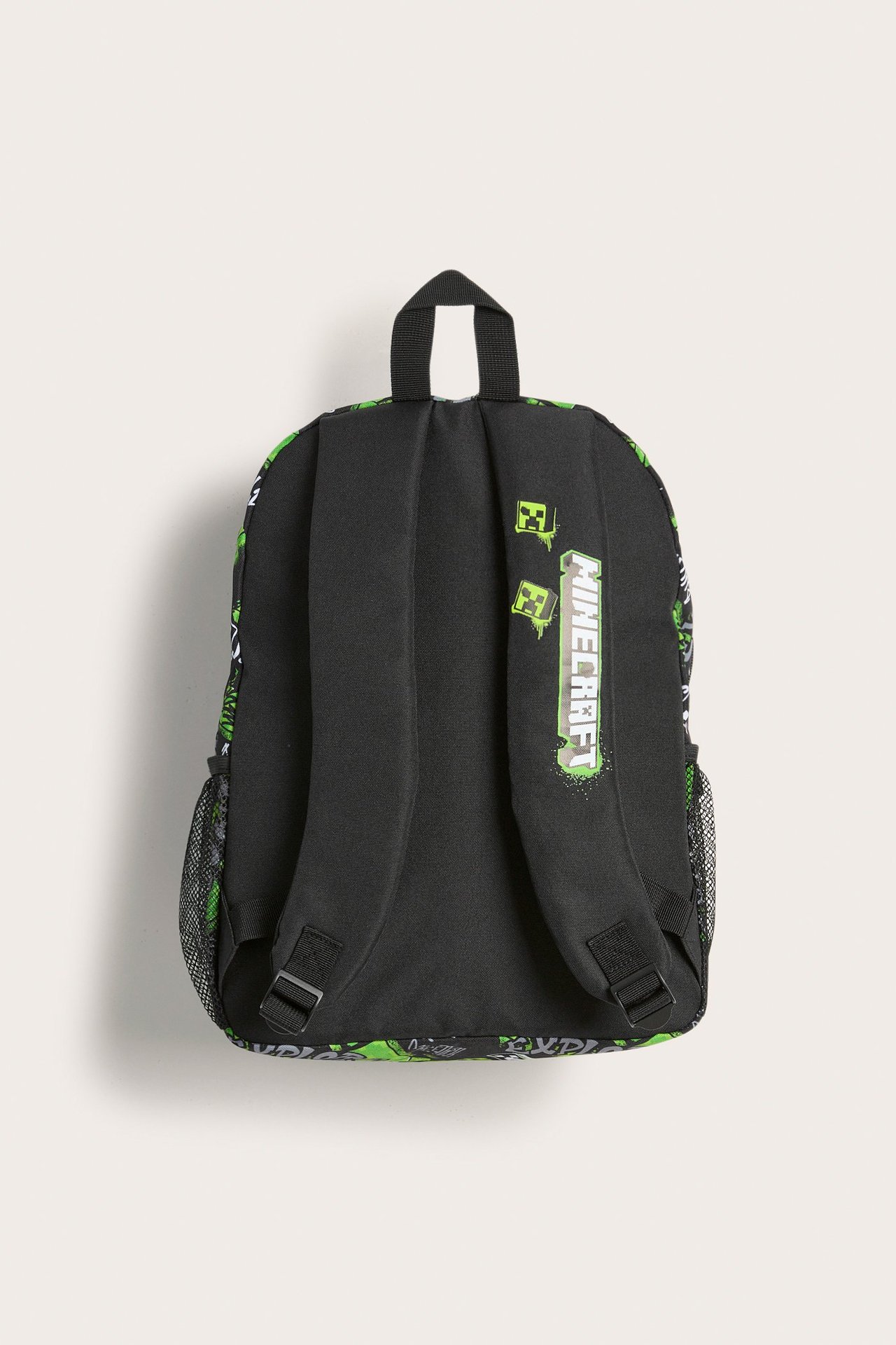 Musta polyesterinen lasten reppu takaa, vihreällä Minecraft-kuviolla, pehmustetuilla hihnoilla ja verkkotaskulla.