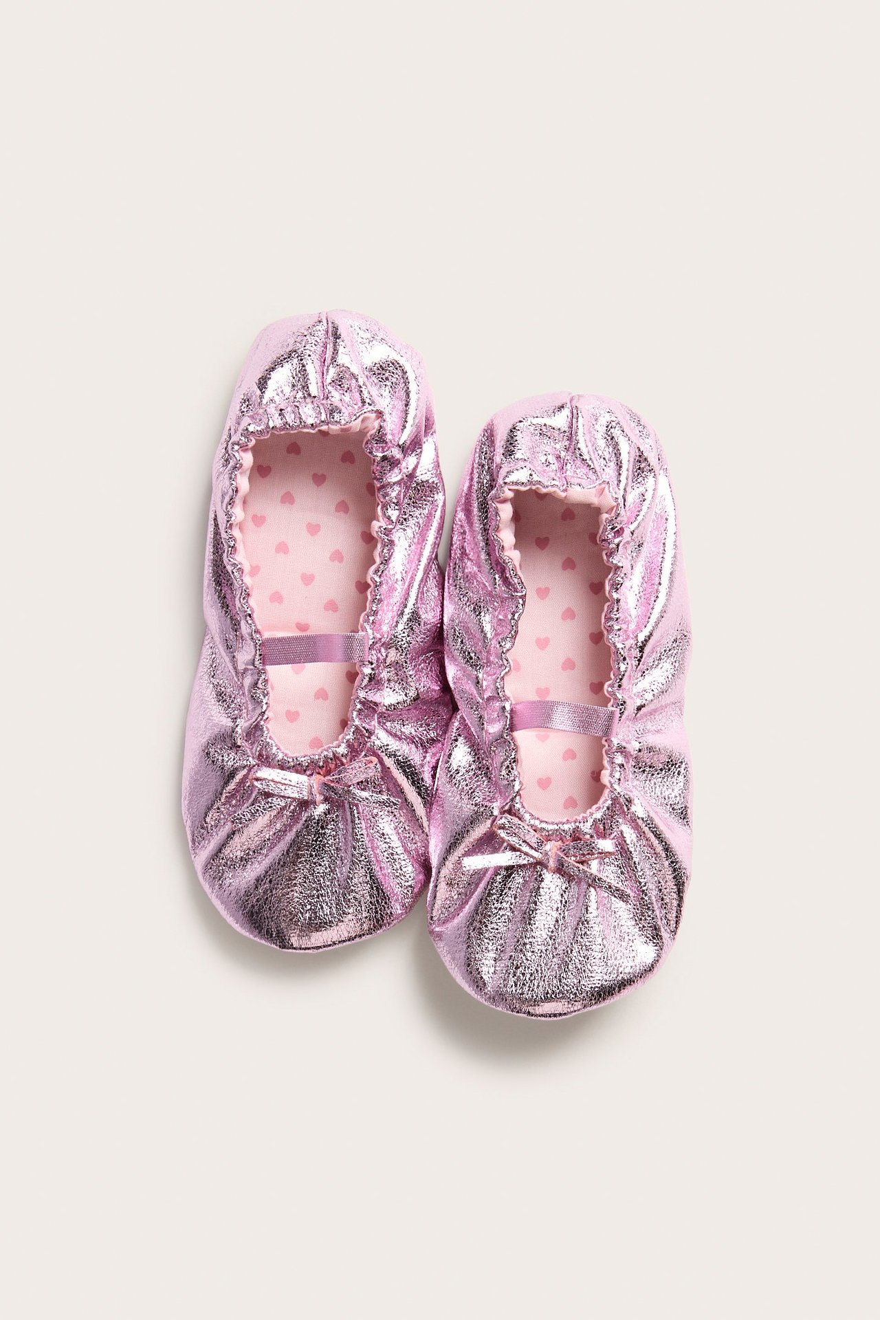 Widok z góry: dwie jasnoróżowe metaliczne baletki z elastycznymi paskami i wkładkami w serduszka.