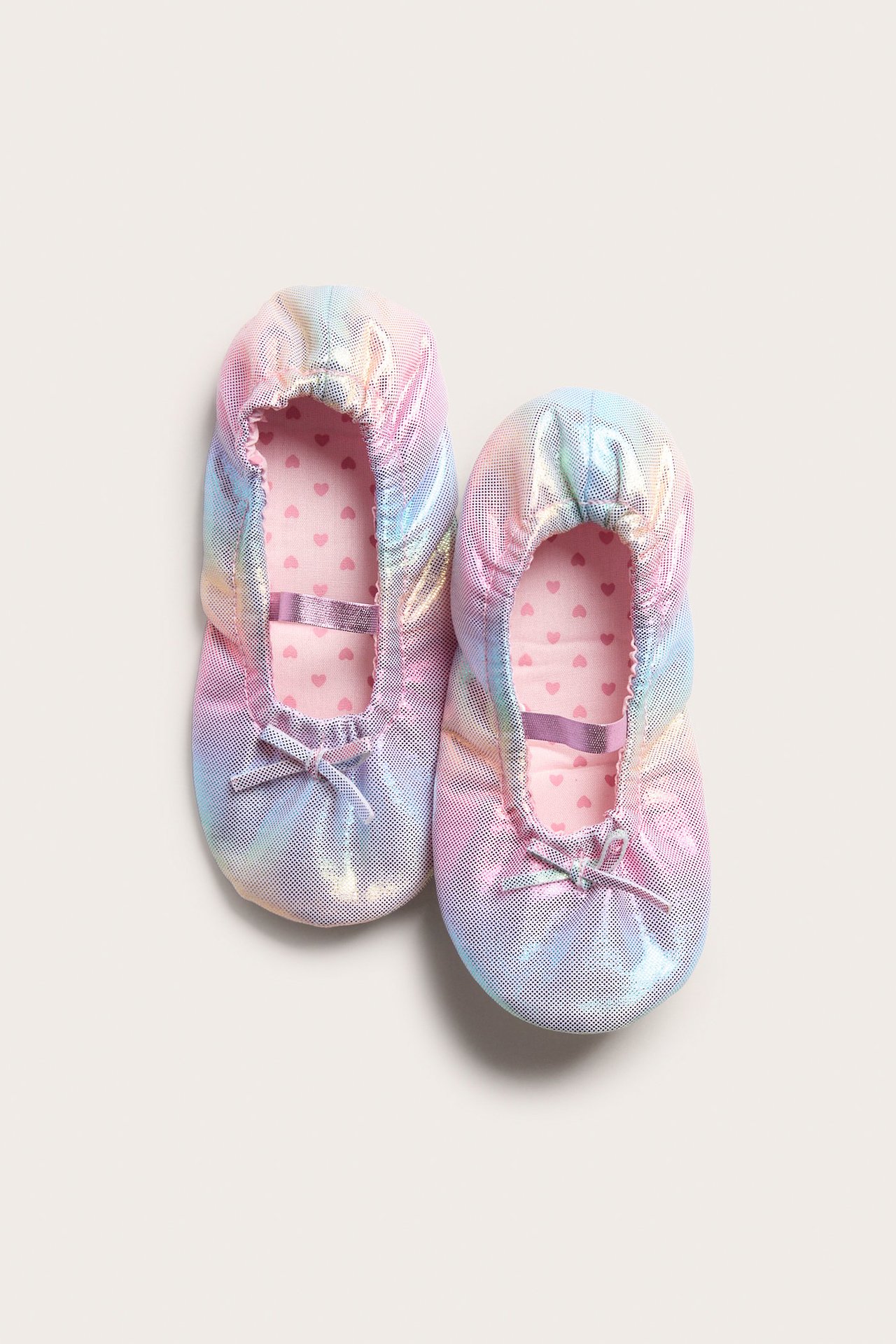 Widok z góry: iryzujące pastelowe baletki z małymi kokardkami i różową podszewką w serduszka.