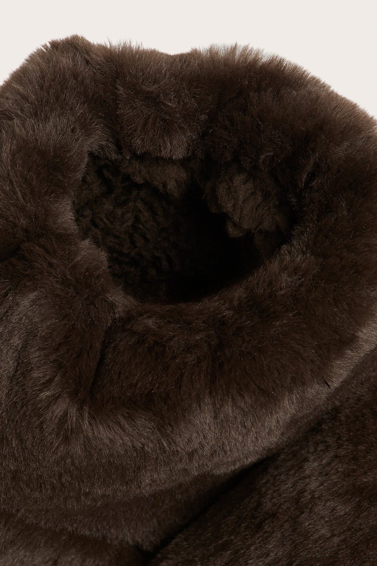 Zbliżenie na ciemnobrązowy, futrzany kapeć-botek z podszewką z polaru.