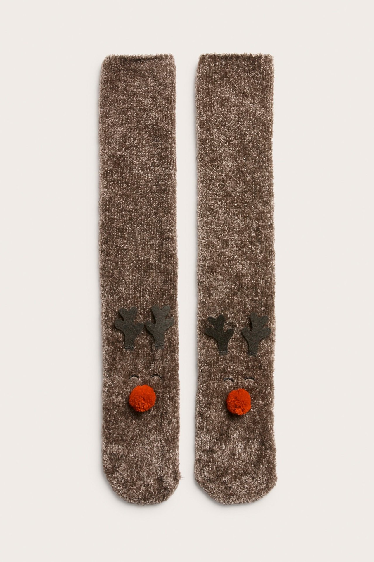 Widok z przodu brązowych skarpet szenilowych z ciemnymi rogami renifera i czerwonym pomponowym nosem.