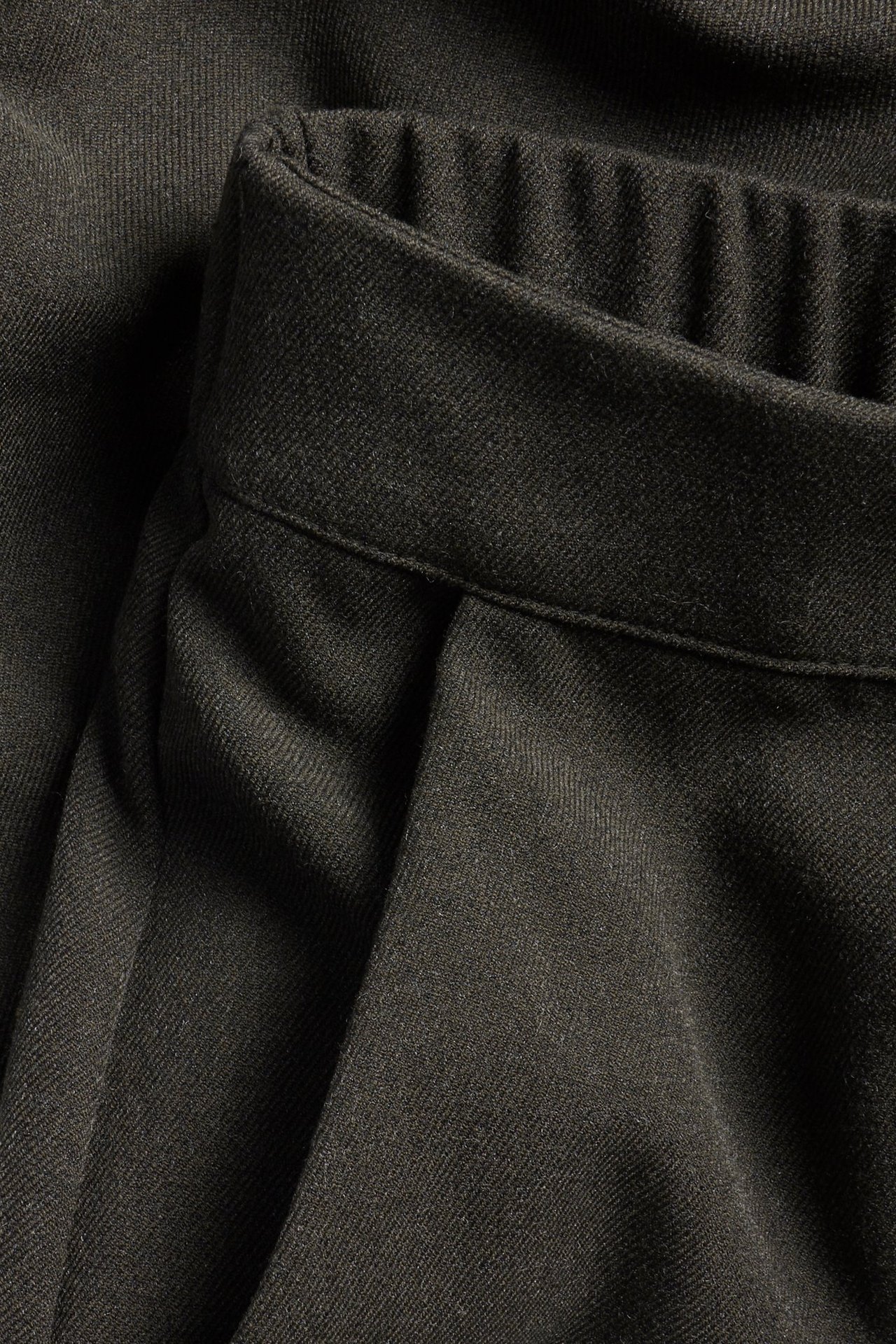 Zbliżenie na ciemnobrązowe spodnie garniturowe z elastyczną talią z tyłu.