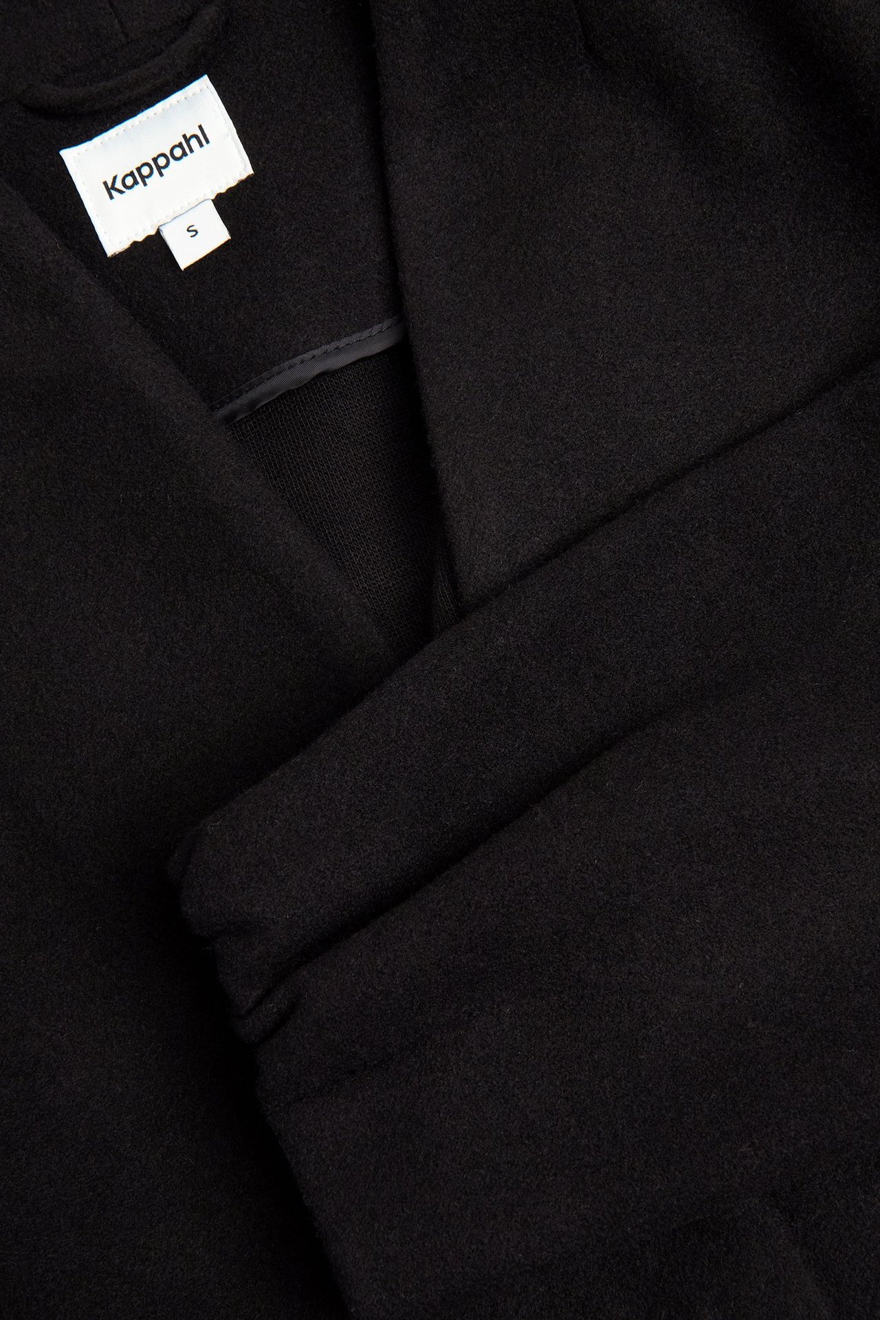 Zbliżenie czarnej, wełnianej kurtki wewnętrznej z otwartym dekoltem w kształcie litery V.