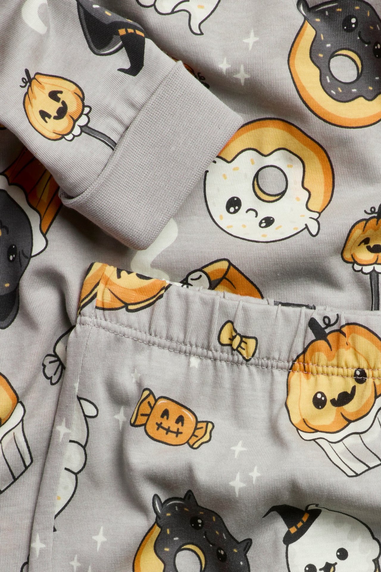 Zbliżenie na szarą bawełnianą piżamę dziecięcą z wzorem Halloween, widać ściągacze i elastyczny pas.