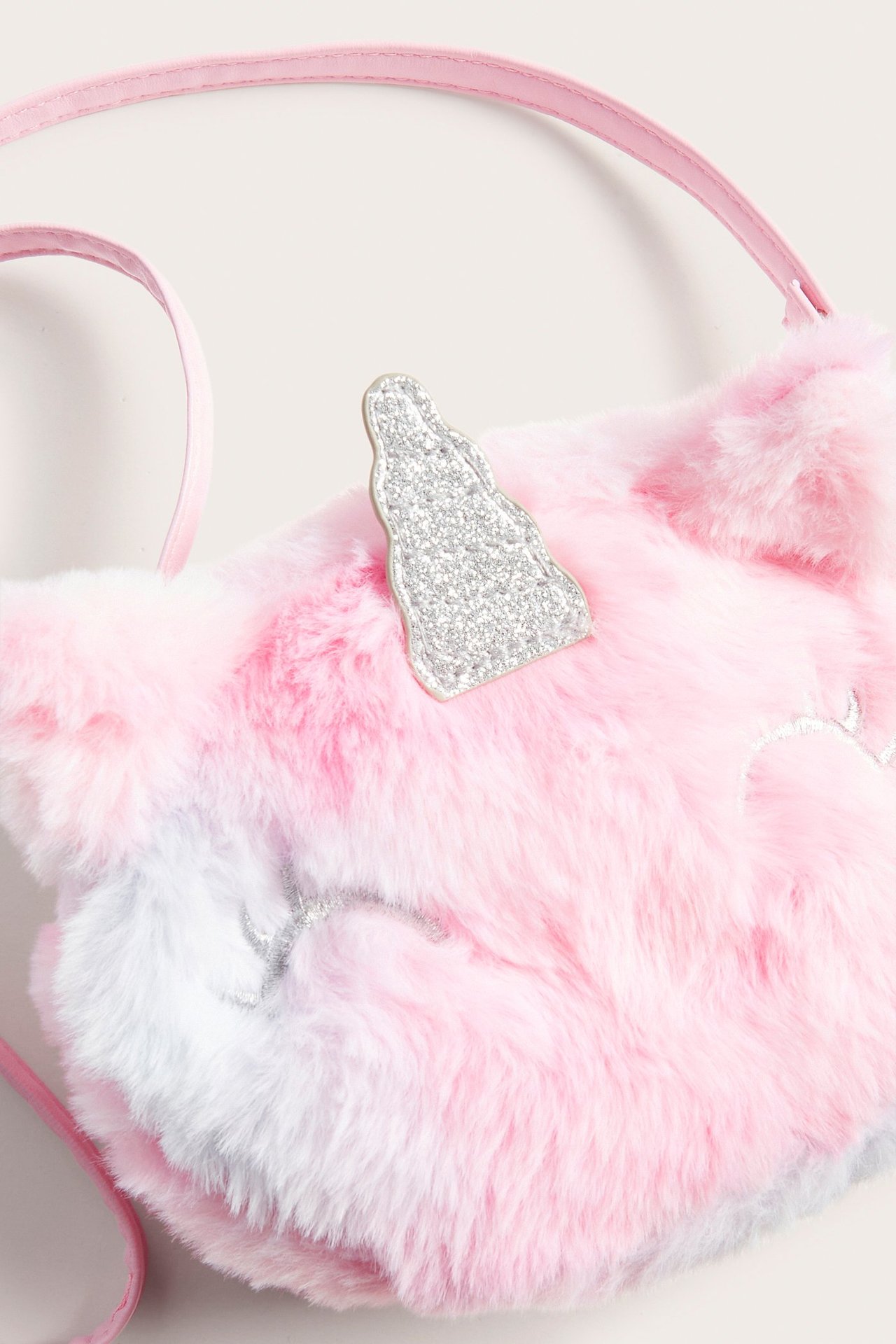 Zbliżenie na dziecięcą różowo-biało-niebieską tęczową torebkę z futra jednorożca z brokatowym rogiem.