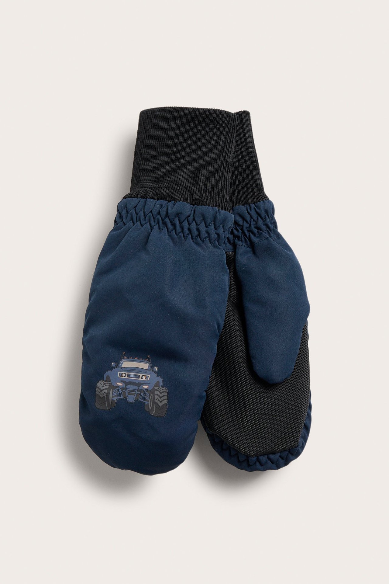Widok z przodu ciemnoniebieskich rękawiczek dziecięcych z czarnymi ściągaczami i nadrukiem monster trucka.