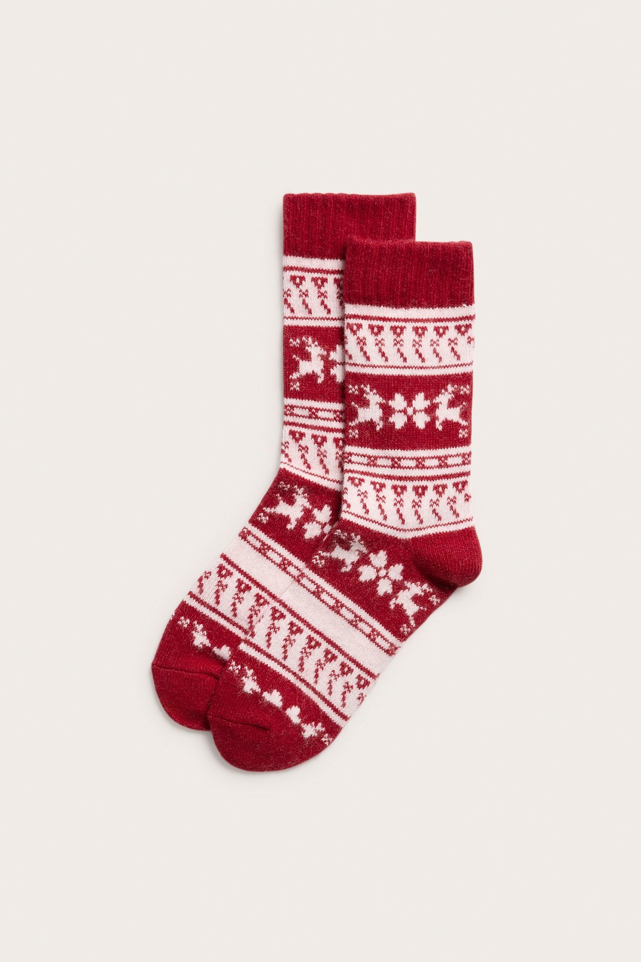 Widok z przodu, dwie czerwone skarpety żakardowe z białymi wzorami reniferów i płatków śniegu.