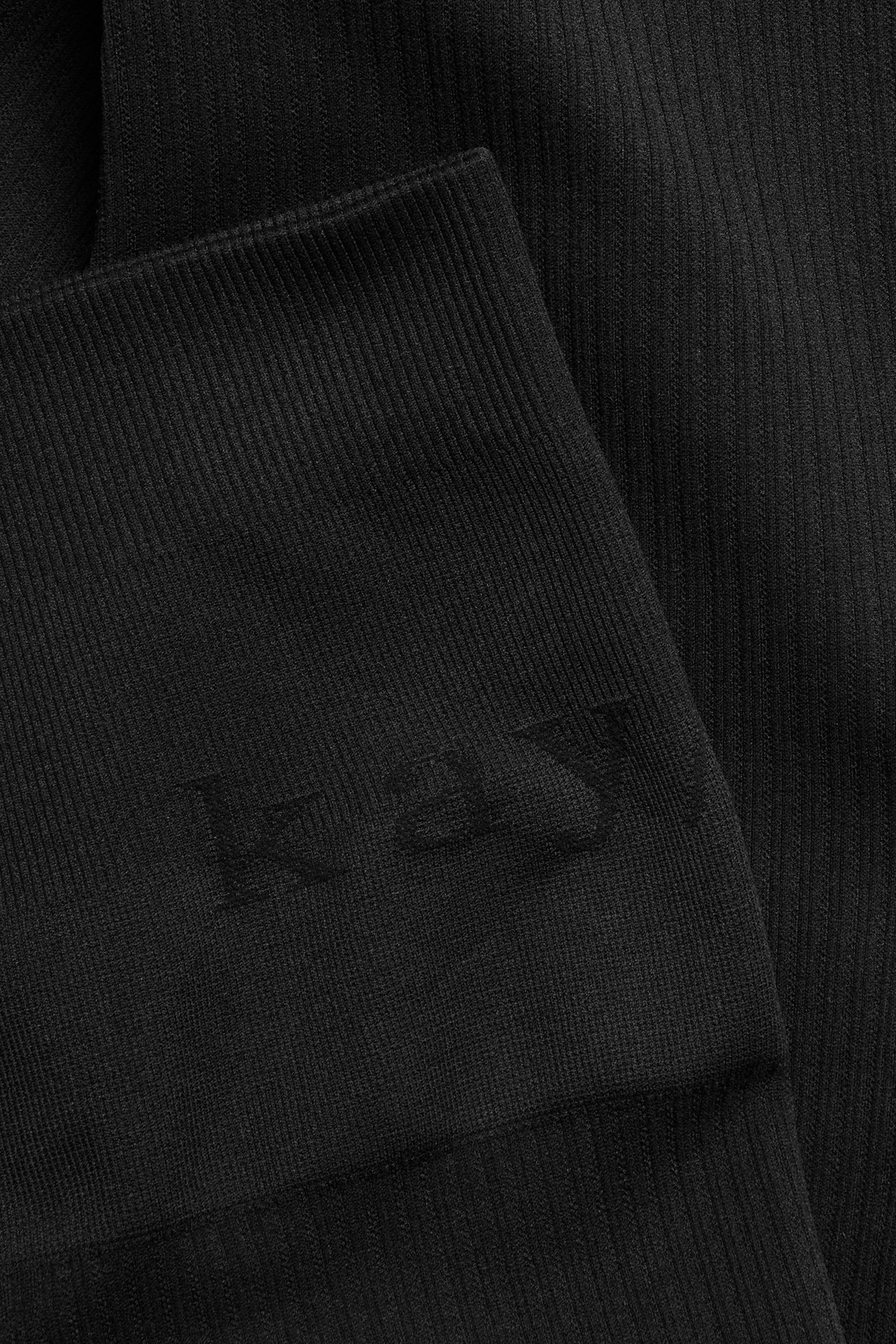 Zbliżenie na czarny prążkowany bezszwowy materiał legginsów treningowych.