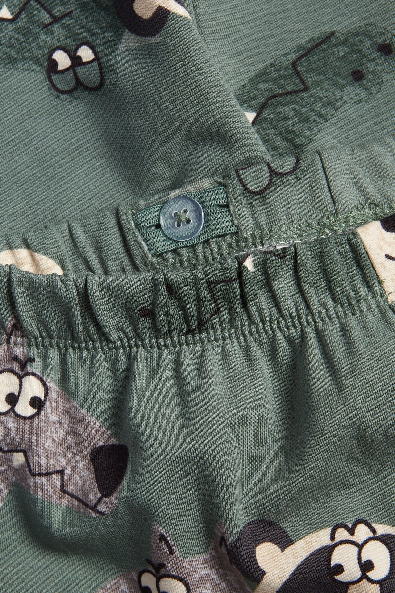 Närbild av mörkgröna barnleggings med djurmönster och justerbar resår i midjan.