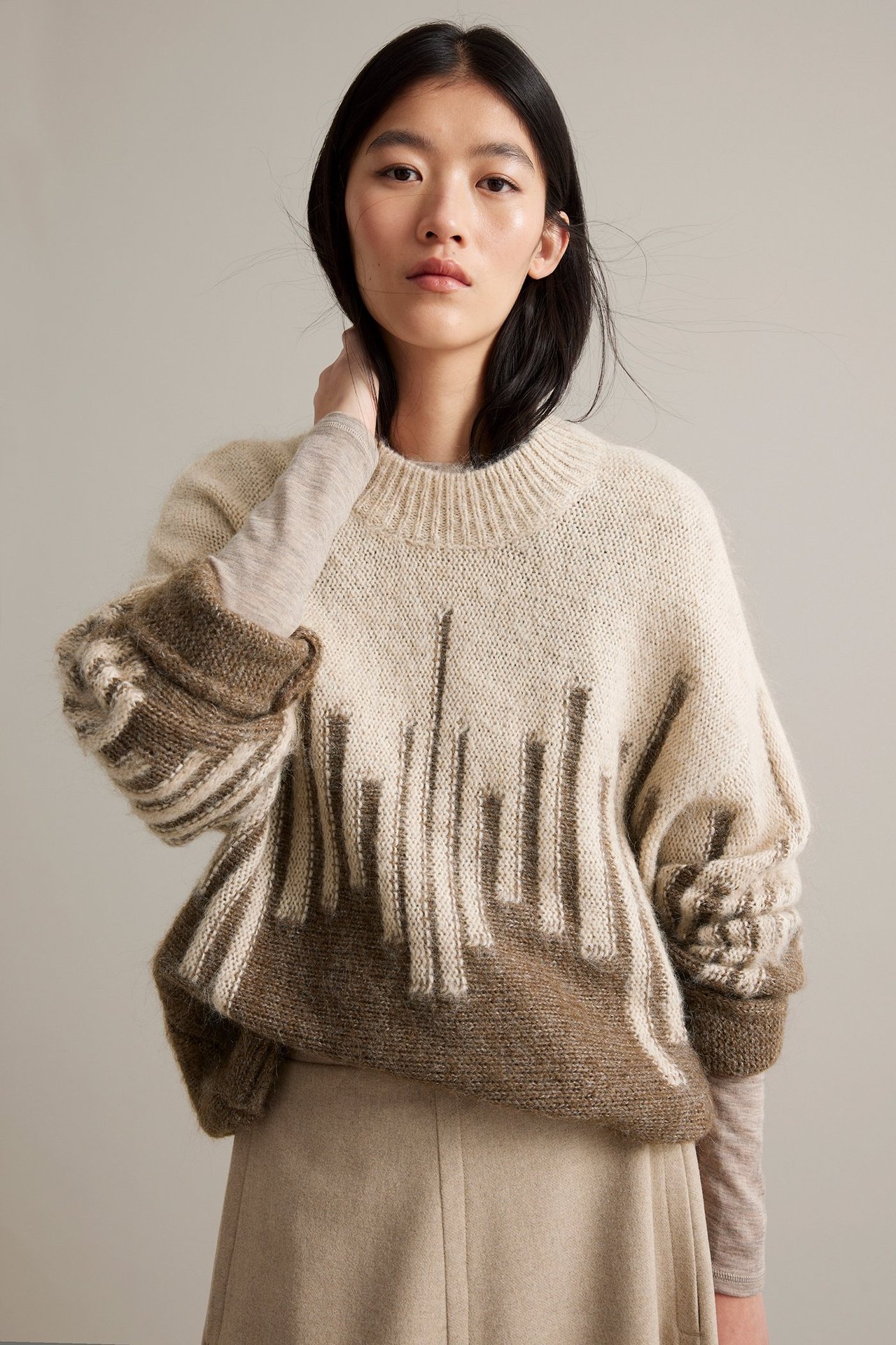 Nainen beige- ja ruskea jacquard-talvivaatteessa, väljä malli, etupuoli.