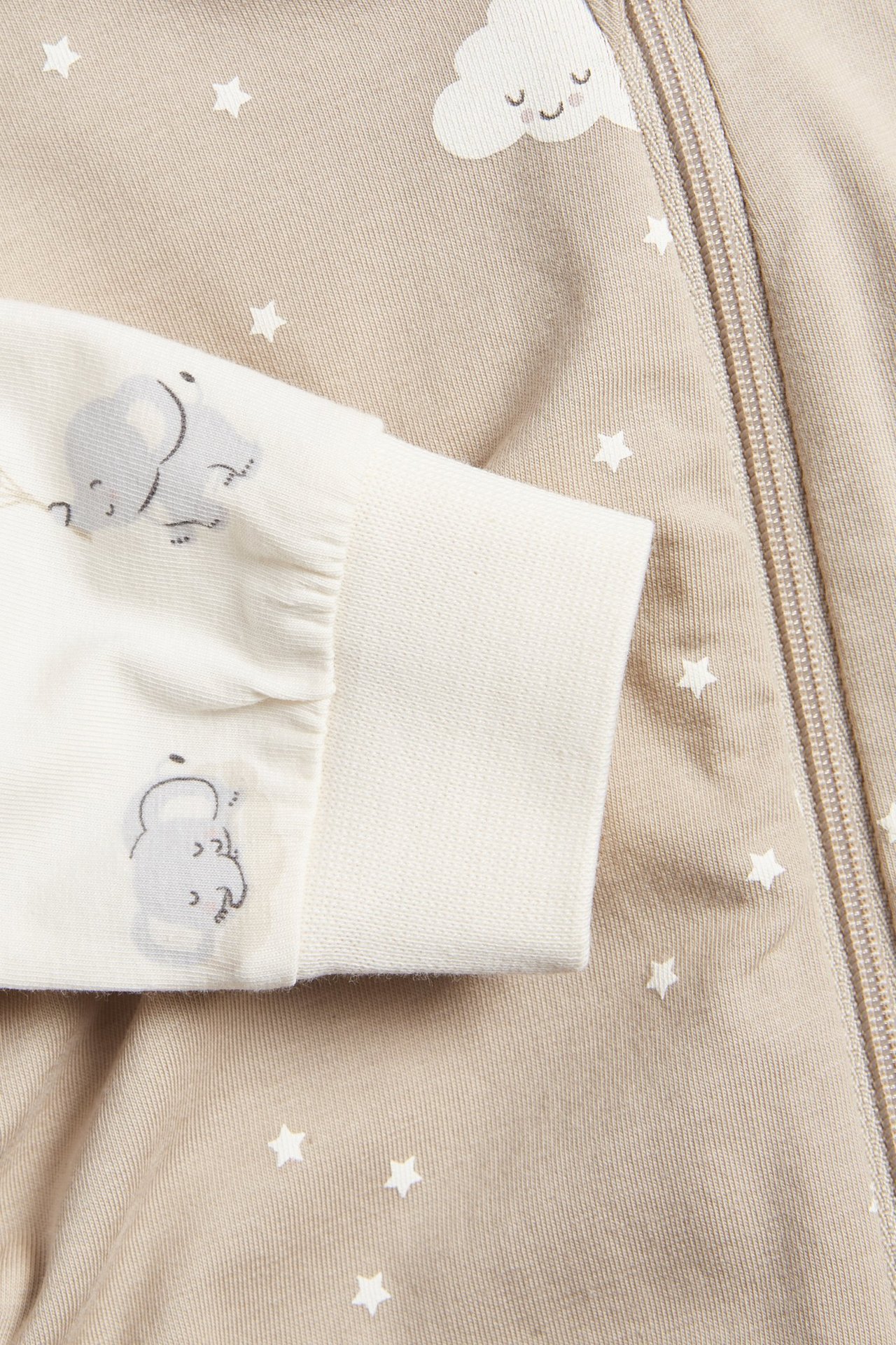 Zbliżenie na pajacyki niemowlęce: rękaw w kolorze złamanej bieli ze słoniami i beżowy pajacyk w gwiazdki z zamkiem.