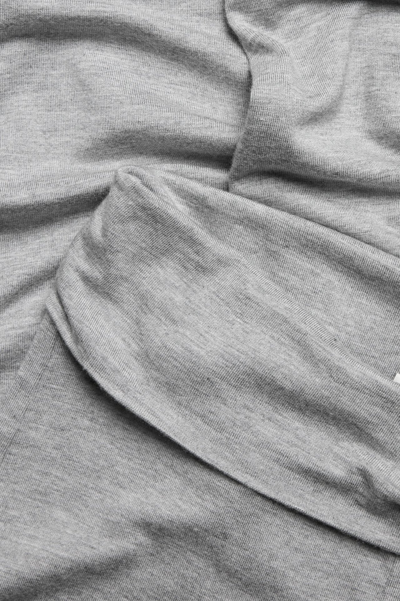 Zbliżenie na jasnoszary melanżowy materiał wiskozowy z rozszerzanych legginsów do jogi.