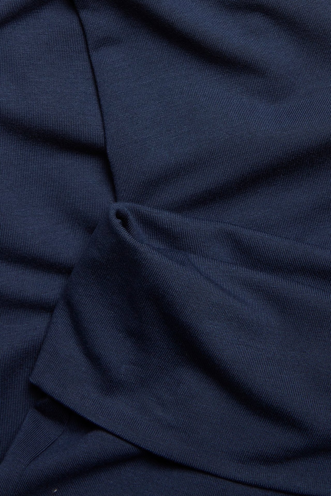 Zbliżenie niebieskiego, prążkowanego materiału z mieszanki wiskozy z legginsów flare, z fałdami.