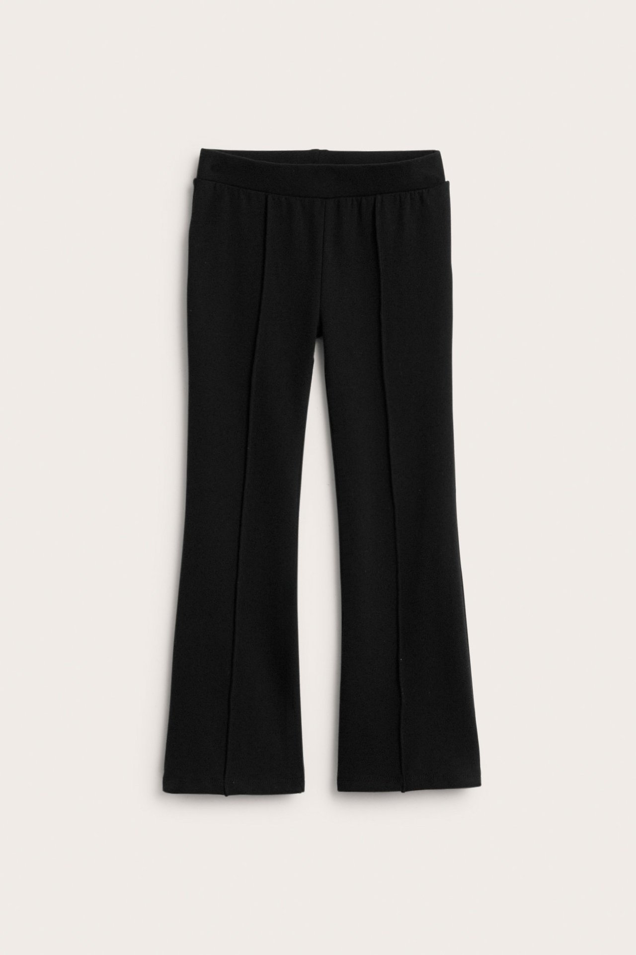 Edestä mustat levenevät trikoohousut prässätyillä saumoilla.