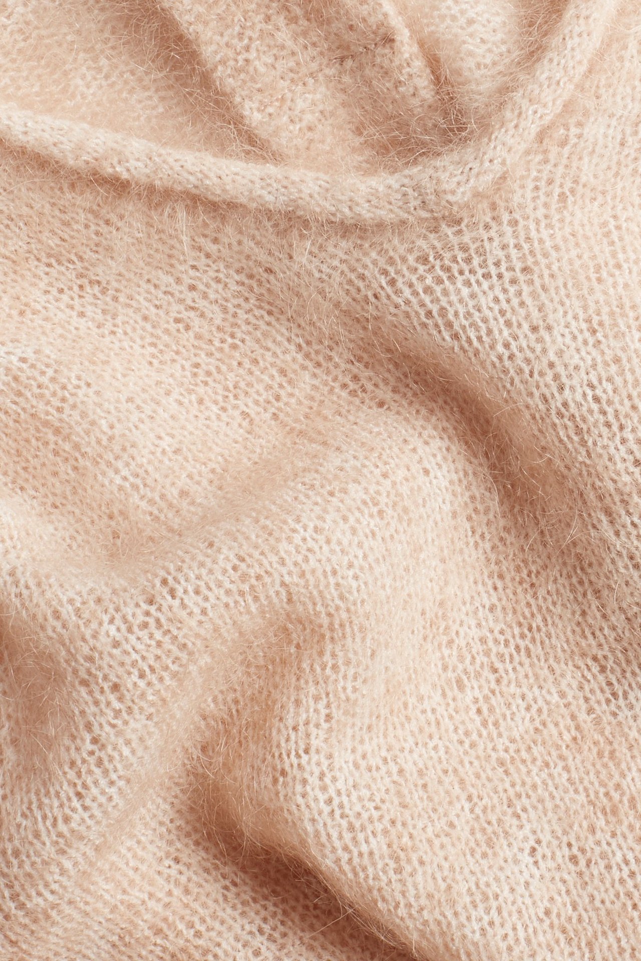 Zbliżenie różowego, dzianinowego swetra z mieszanki moheru, ukazujące jego miękką, puszystą teksturę.