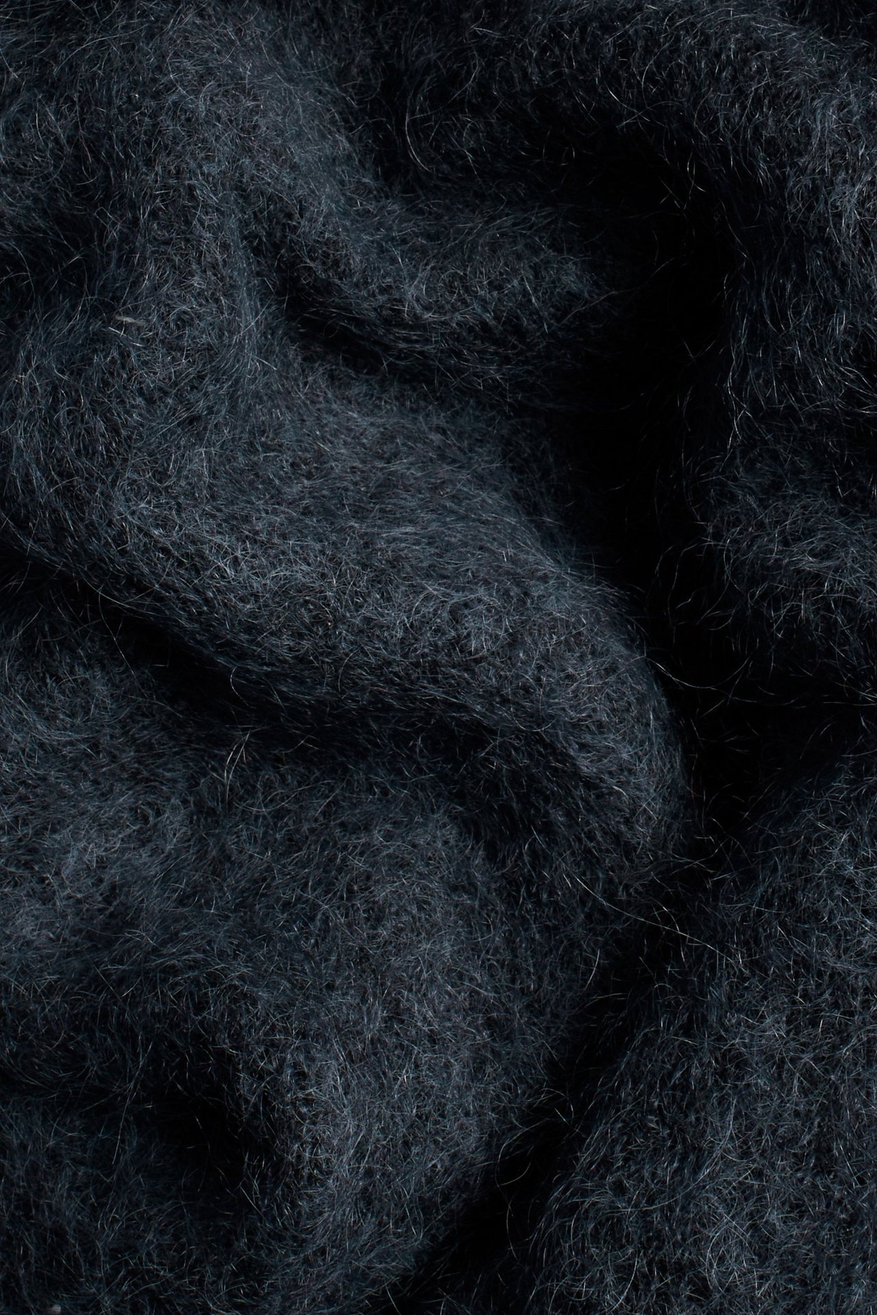 Zbliżenie na ciemnoniebieski sweter z puszystej dzianiny z domieszką moheru.