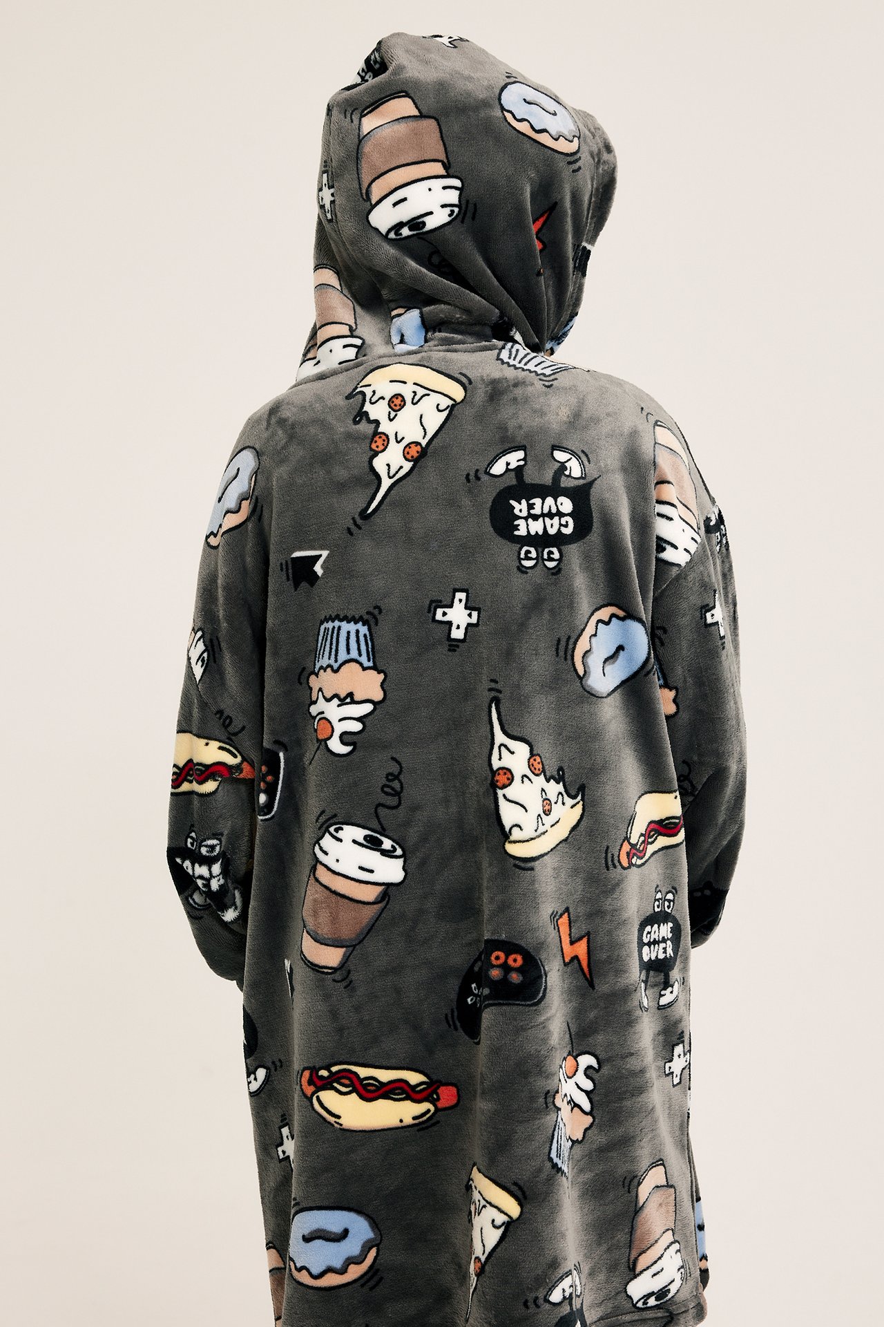 Bakifrån en kid i en mörkgrå mönstrad fleecehoodie med spel- och matmotiv.