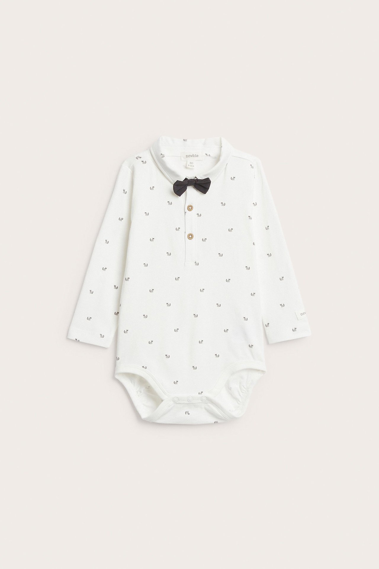 Framsida: Offwhite långärmad babybody med djurmönster, krage, knappar fram och svart fluga.