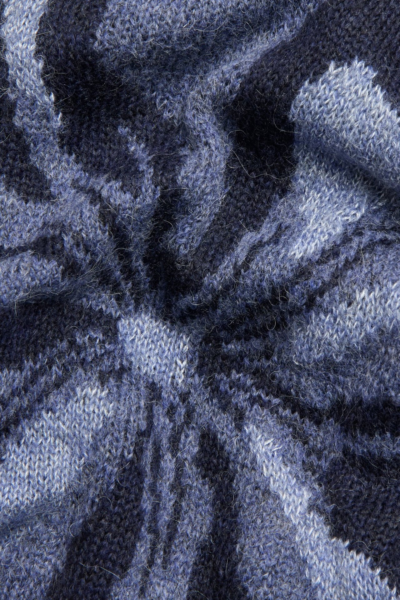 Zbliżenie niebieskiego swetra z dzianiny intarsjowej w kwiatowy wzór.