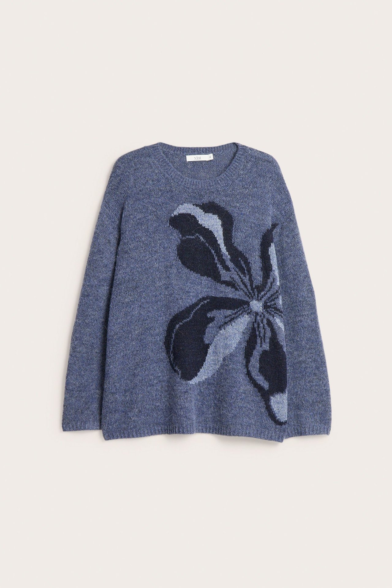 Widok z przodu niebieskiego swetra z intarsją i dużym, ciemnoniebieskim wzorem kwiatowym.