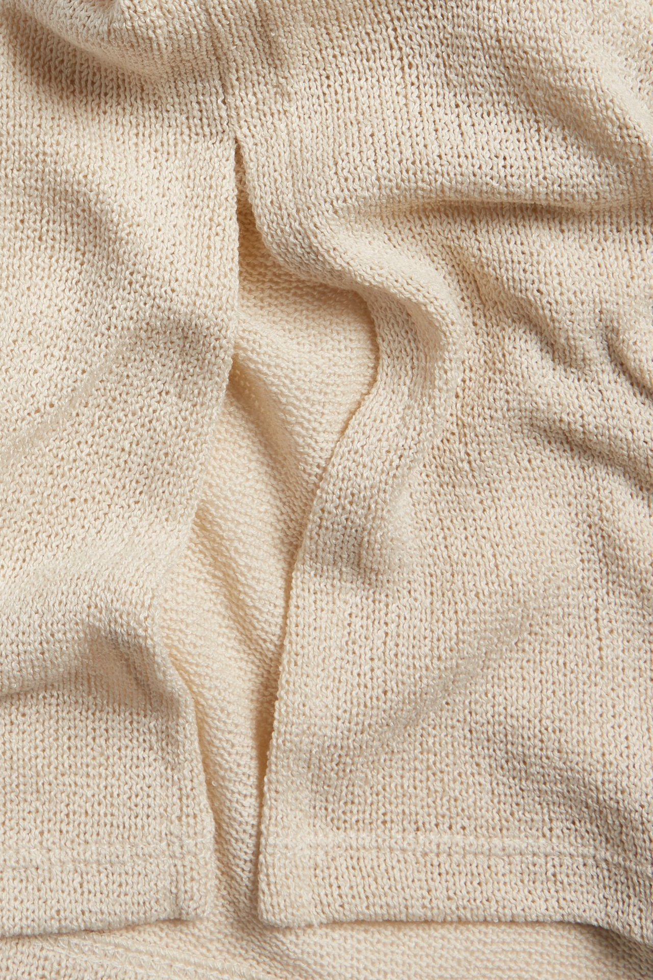 Zbliżenie na kremowy, teksturowany materiał poliestrowy, przypominający len, z widocznymi zagnieceniami.