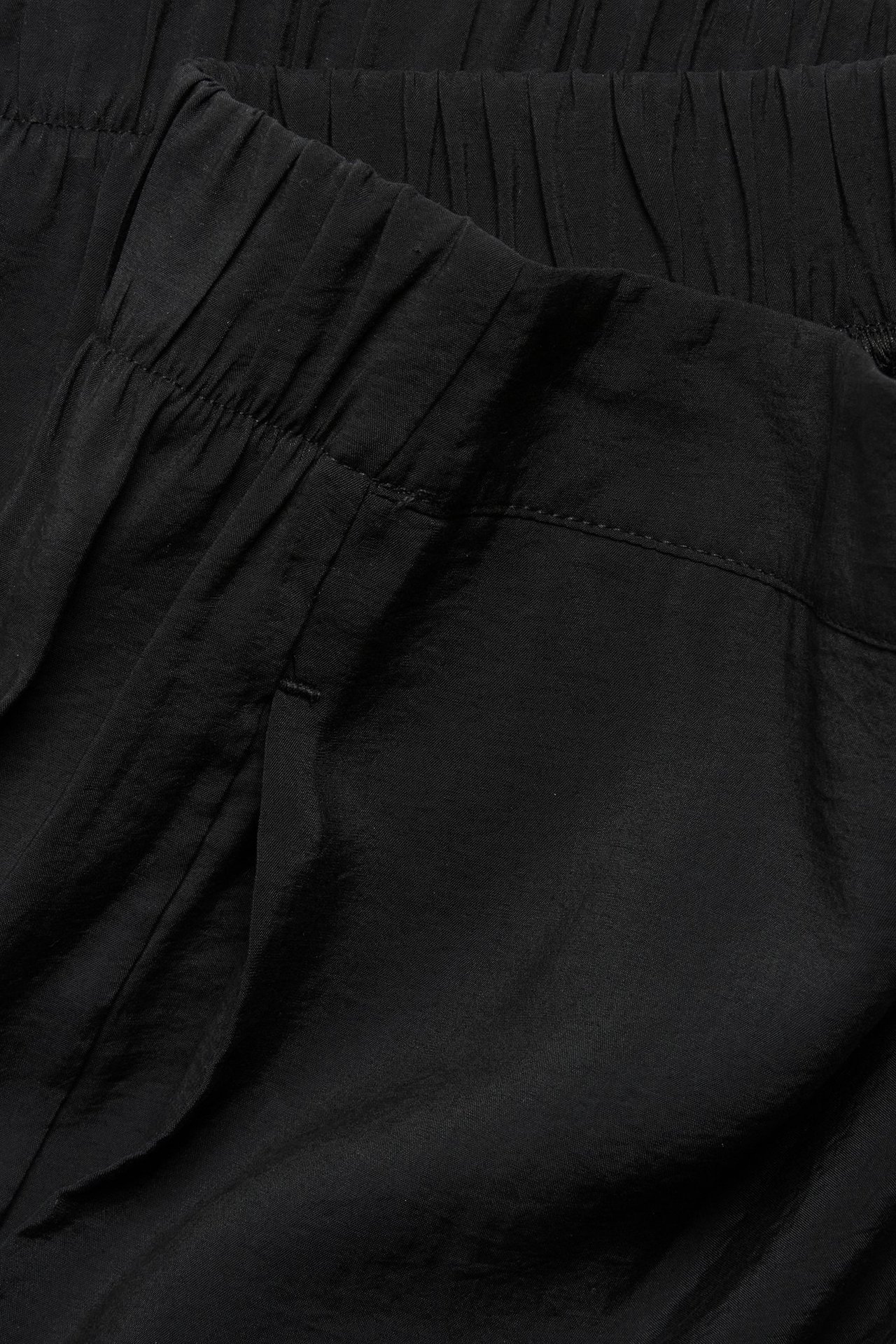 Zbliżenie czarnych szerokich spodni pull-on z elastyczną talią, wykonanych z mieszanki modalu i poliestru.