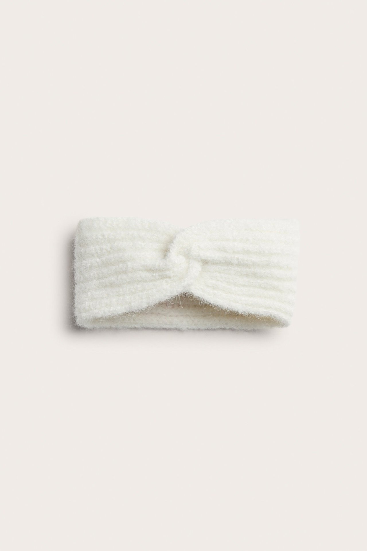 Zbliżenie, widok z przodu na białe, prążkowane opaska na głowę ze skręconym detalem.