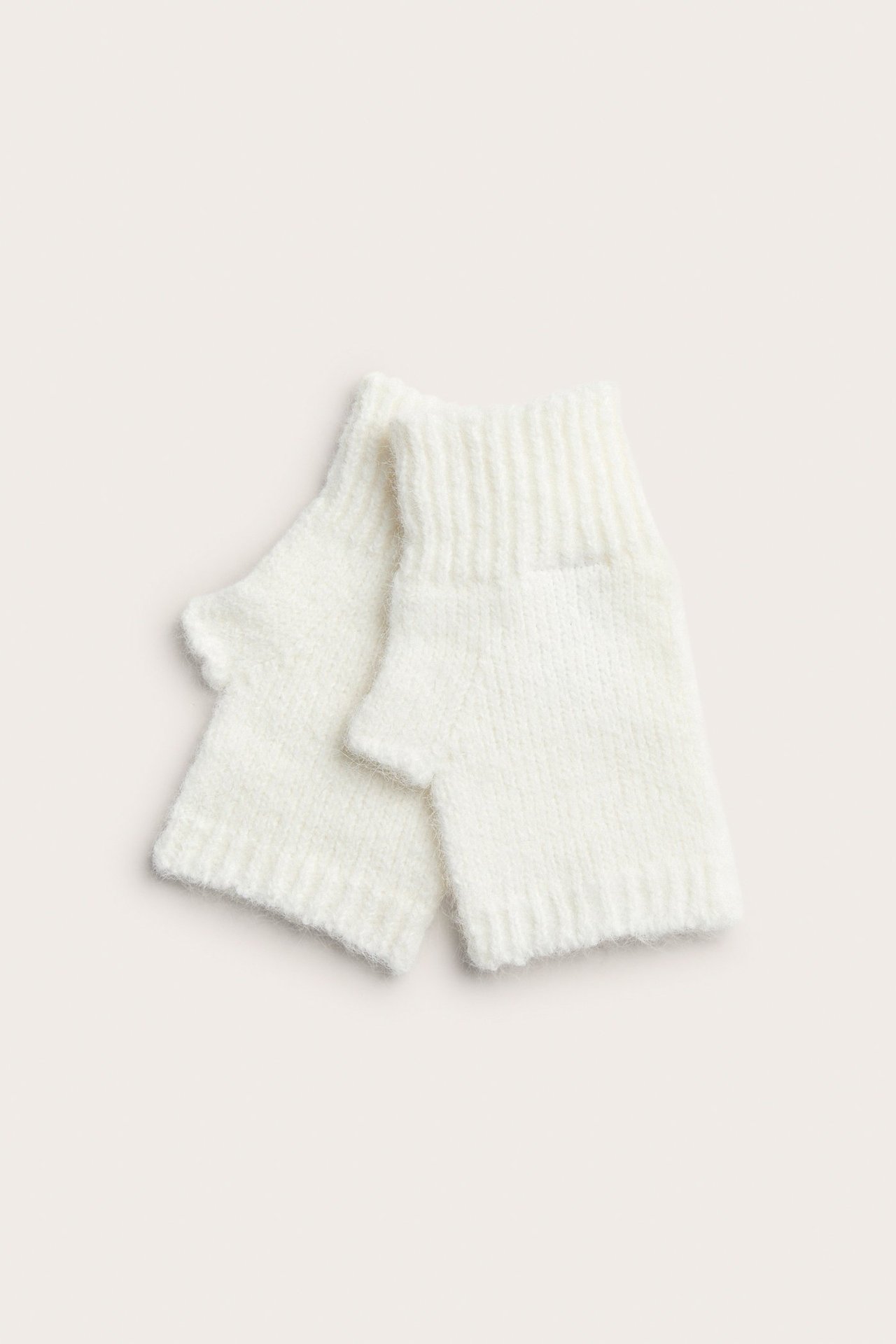 Yläkuva kahdesta pehmeästä, valkoisesta ribbineulotusta ranteenlämmittimestä.