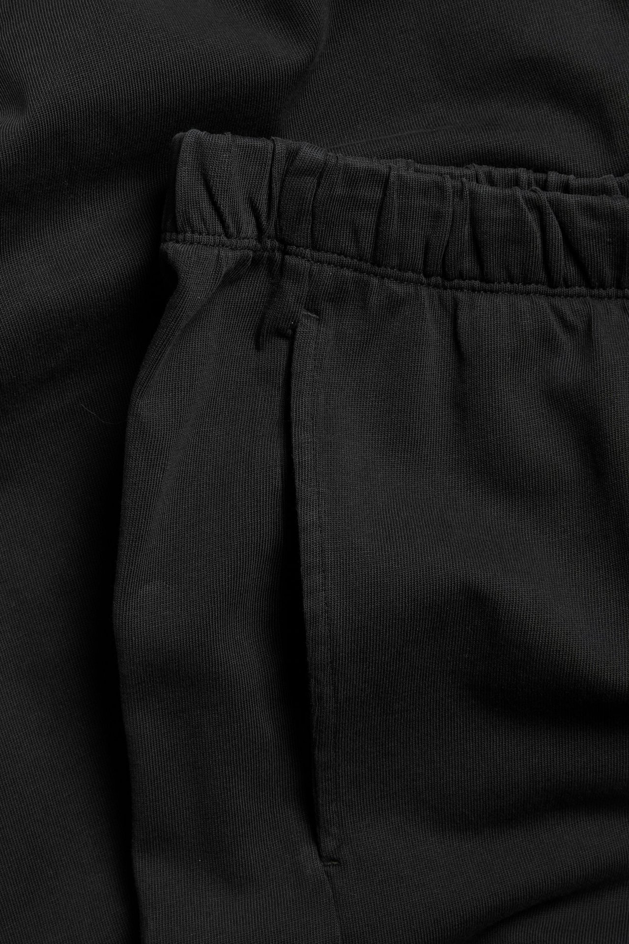 Zbliżenie na czarne proste bawełniane joggery z elastycznym pasem i boczną kieszenią.