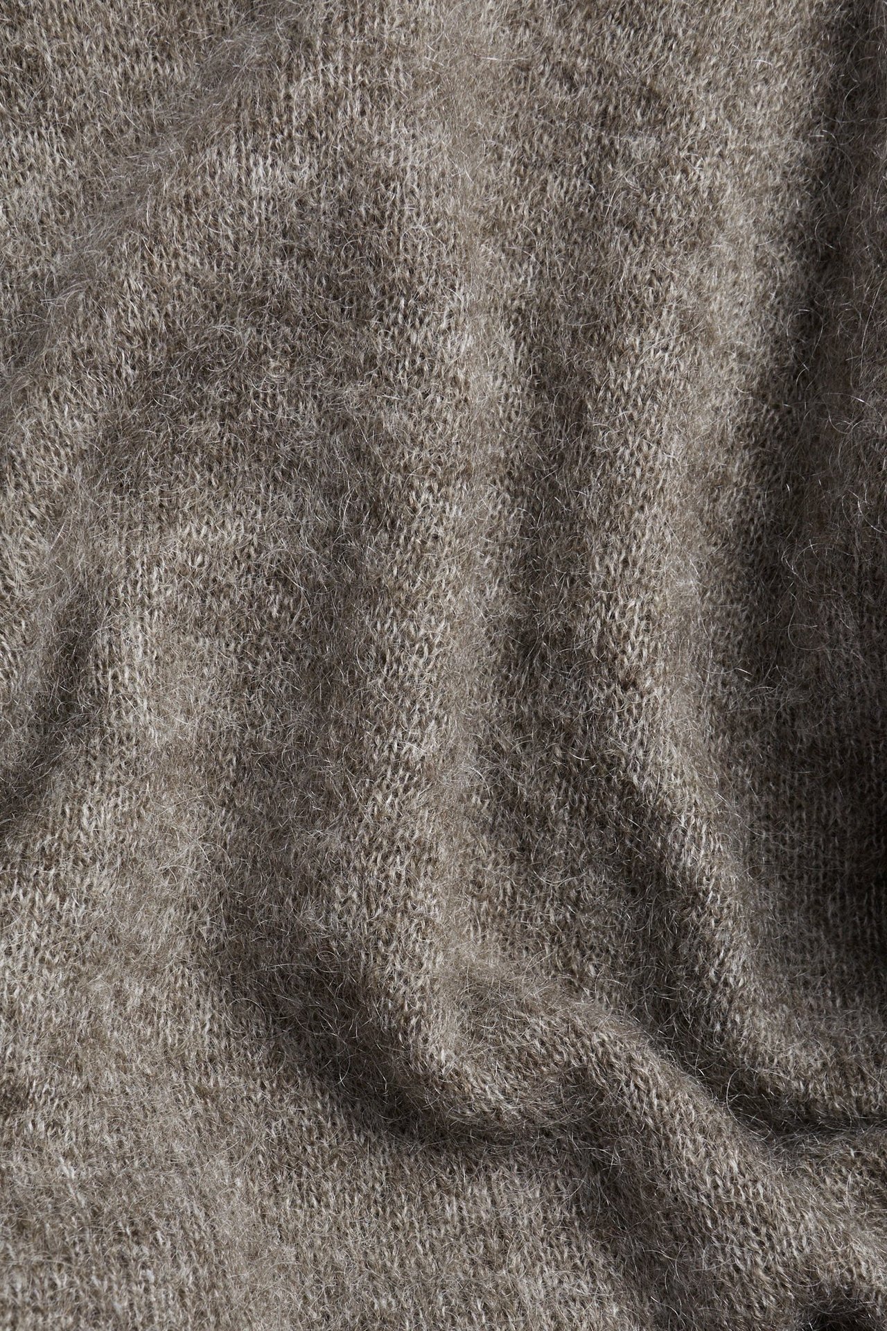 Zbliżenie brązowego melanżowego swetra z dzianiny z domieszką moheru, ukazujące jego teksturowaną tkaninę.