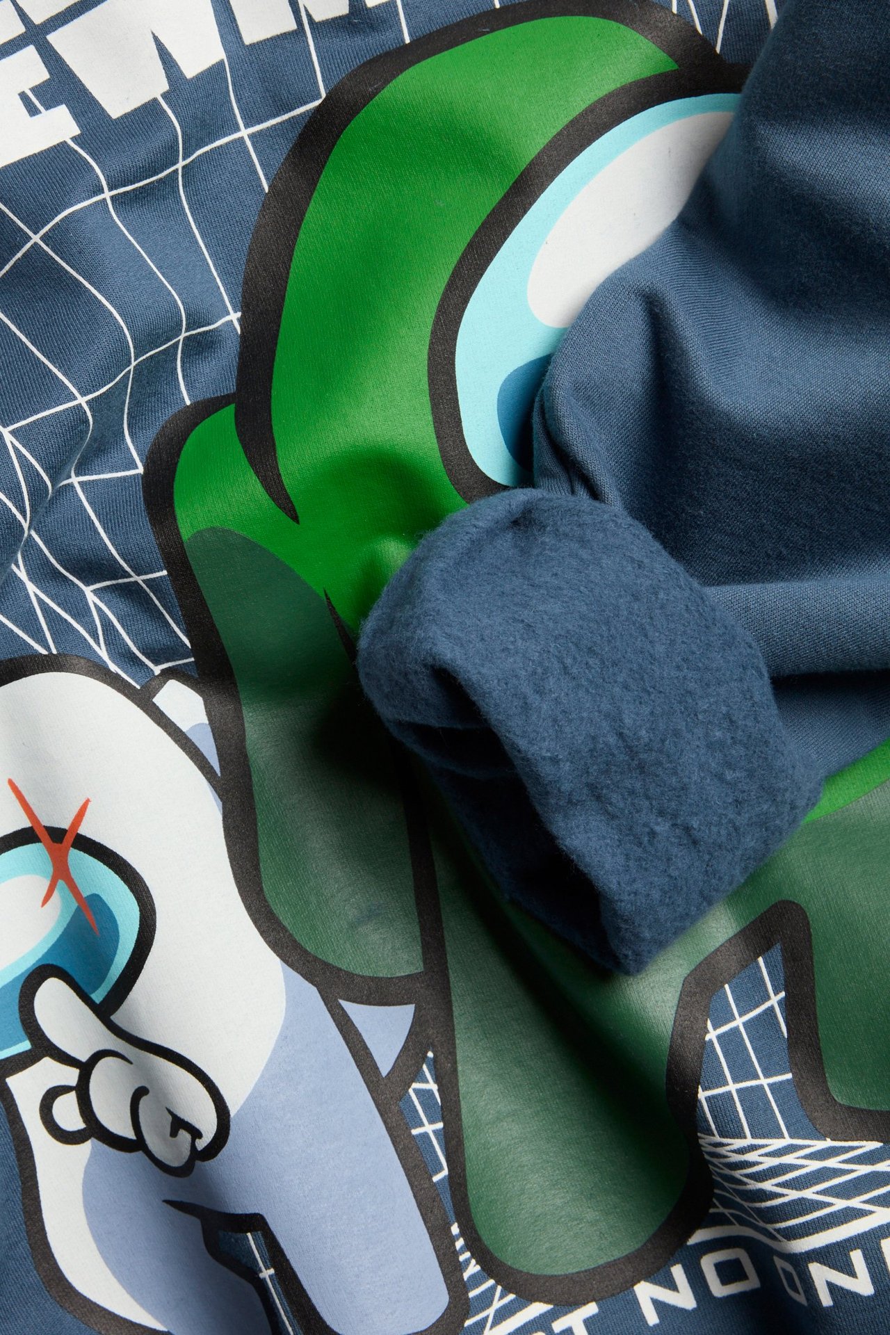 Zbliżenie niebieskiej bawełnianej bluzy z dużym nadrukiem Among Us i widocznym szczotkowanym miękkim wnętrzem.