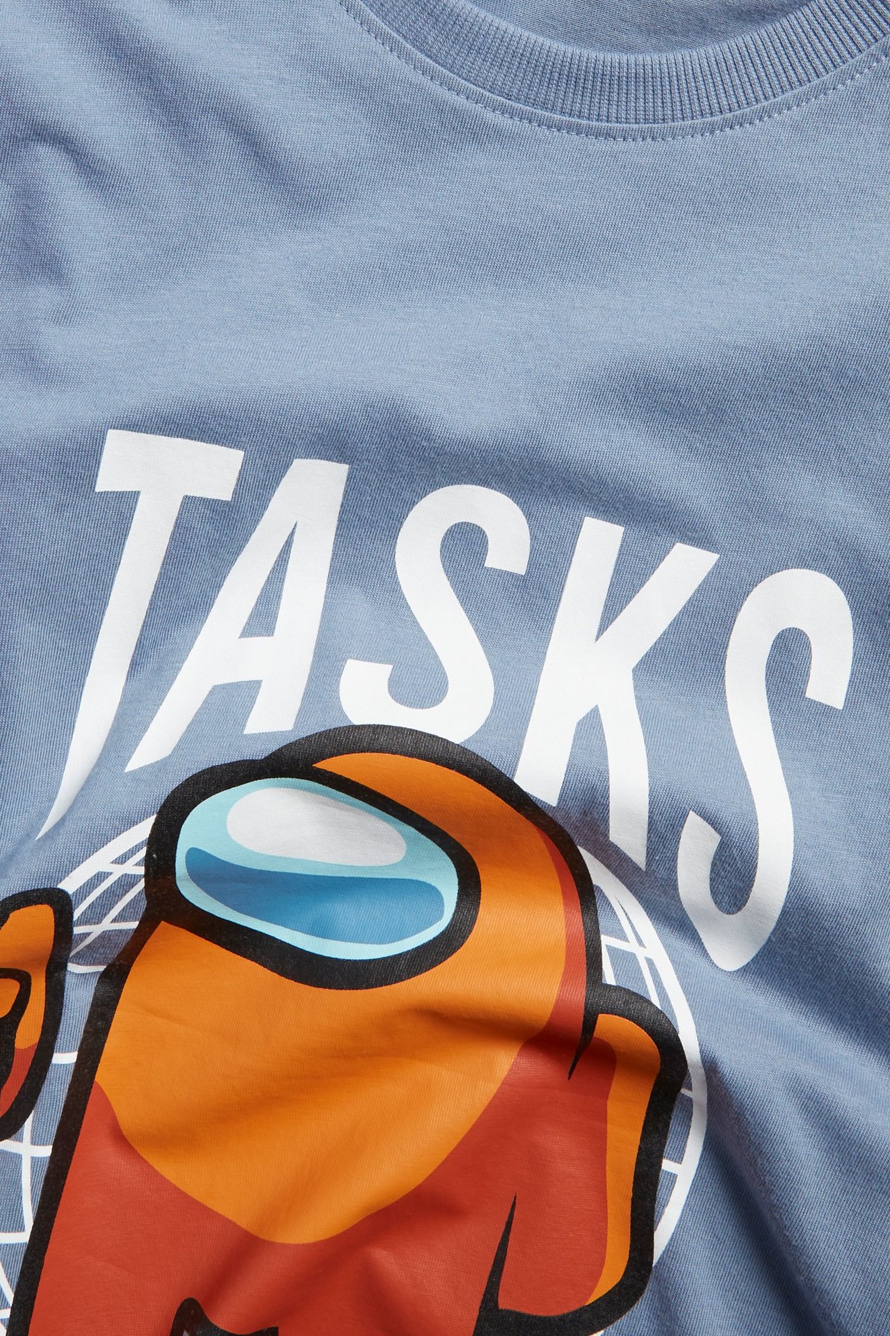 Närbild på en ljusblå bomulls-t-shirt för barn med ett orange Among Us-karaktärstryck.