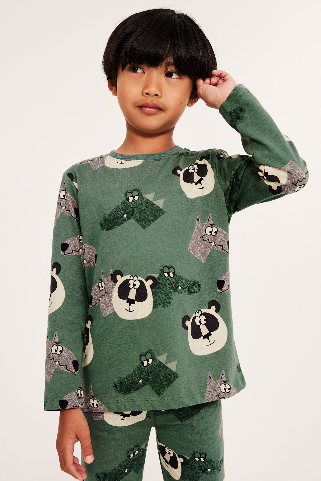 Edestä: Lapsi tummanvihreässä puuvillaisessa pitkähihaisessa paidassa eläinkuviolla ja yhteensopivissa housuissa.